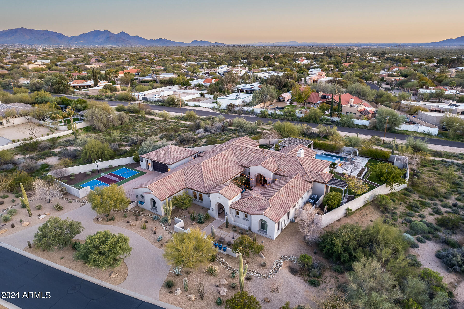 The epitome of luxury! This gorgeous 5-bedroom single-story estate is situated on 1.6 acres in the coveted Saguaro Estates neighborhood with mountain views all around. Enter through the welcoming string-lit courtyard and admire the 14' disappearing glass sliding door as you step inside, as well as a stacked stone fireplace feature wall. The chef's kitchen includes top-of-the-line stainless steel appliances like sub-zero refrigerators, double ovens, a Wolf cooktop, and two dishwashers. The massive kitchen island is the center of the home, plus there's also a breakfast nook and a dry bar with a wine fridge. The primary wing includes a large bedroom, private office, two walk-in closets, and a spa-like bathroom with a soaking tub and dual-entry shower with twin shower heads + side jets. Treat your family and guests to comfort and privacy with a floor plan that has generously-sized bedrooms with ample closet space, as well as a versatile den / play room and a second family room off of the kitchen with another 14' glass slider to the backyard. There's even an attached 1-bedroom casita with its own entrance, kitchenette, bedroom, and bathroom. Outside is an entertainer's dream with a stunning multi-level pool that has a spa, diving board, waterslide, and swim-up bar. The outdoor kitchen features a sink, mini fridge, barbecue, and hibachi grill under a cantilevered pergola. Additional features in the backyard oasis include three covered travertine patios, two firepits, an in-ground trampoline, a putting green, an outdoor cedar shower, and large artificial grass areas for any activities you want to do. Out front by the 6-car garage (4-car + 2-car or RV detached) is a multi-use pickleball / basketball court to add to the other activities. Other thoughtful upgrades to note are epoxy floors in the garages with overhead storage + EV charging ports, dual instant hot water heaters, and two washer and dryers in the laundry room. Along with this home having everything you could need, it's also close to shopping, dining, and incredible golf!