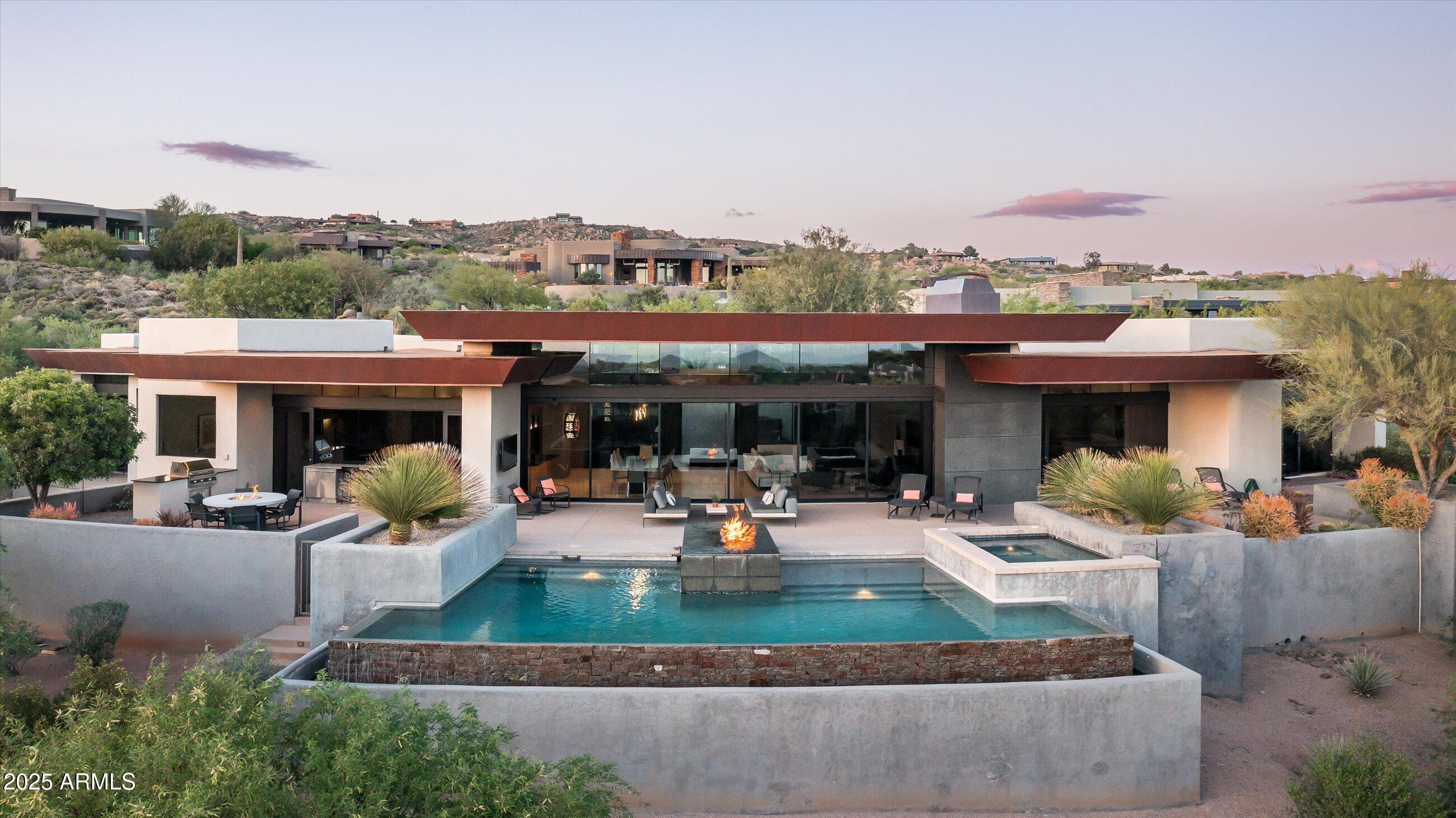 THE DESERT MOUNTAIN HOME YOU HAVE BEEN WAITING FOR ** GOLF MEMBERSHIP AVAILABLE** MODERN CONTEMPORARY WITH PROTECTED MOUNTAIN, GOLF COURSE, CITY LIGHT AND SUNSET VIEWS**  NO STEPS** This amazing home offers a Desert Mountain buyer the rare opportunity to own a contemporary home with a timeless modern aesthetic.  The Great Room's floor to ceiling double-sided fireplace wall is the focal point of the home.  A bank of automated glass retracts to bring the outside in.  North/south exposure provides all day sun while relaxing by the pool or spa.  A pool fire feature is the perfect backdrop for enjoying sunsets and city lights. Entertaining starts from the bar top and flows into a large kitchen featuring modern wood cabinetry, a large island that seats 6, two sinks, two dishwashers, and a large butler's pantry with additional dishwasher.  The Primary bedroom retreat has its own fireplace and spa-like bath complete with soaker tub and an indoor/outdoor shower.  The guest wing has two bedrooms with ensuite baths.  A 630 sq. ft. two-room casita offers an additional flex place (office, family room, fitness) and a separate guest bedroom and bath.