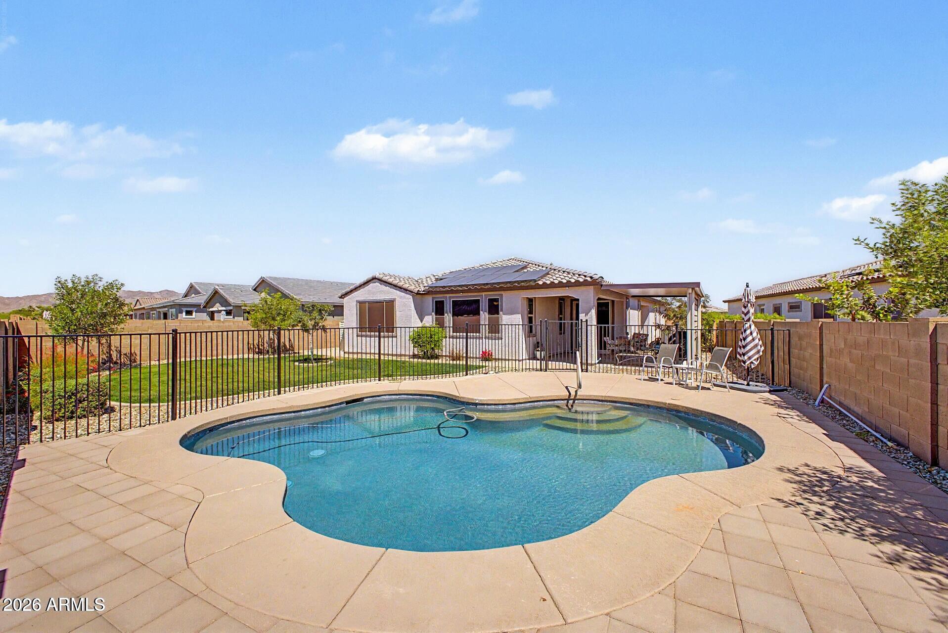 Experience this 4-bed, 3-bath split floorplan that was made for the way you actually live! Everyone gets their own space, including a luxurious primary suite w/ an oversized shower, dual sinks, & a massive walk-in closet, PLUS a private guest ensuite for visitors. The kitchen is the heart of the home featuring a gas range, quartz counters, a massive island w/ pendant lighting, pull-out shelves, & an RO system. Tile runs through all the right spaces w/ hypoallergenic carpet tucked into the bedrooms. Step outside to enjoy the backyard retreat finding an oversized lot w/no homes behind you, a refreshing color-lit saltwater pool, extended covered patio to enjoy sunset gatherings & real grass for your pups to get their zoomies out! Stay comfortable year-round w/ 3-zone climate control & energy- efficient shade screens. The 2 car garage adds overhead storage and a tankless water heater for everyday convenience. 
Minutes from Loop 303, the White Tank Mountains, grocery stores, and restaurants -- this one checks every box. Come see it today!