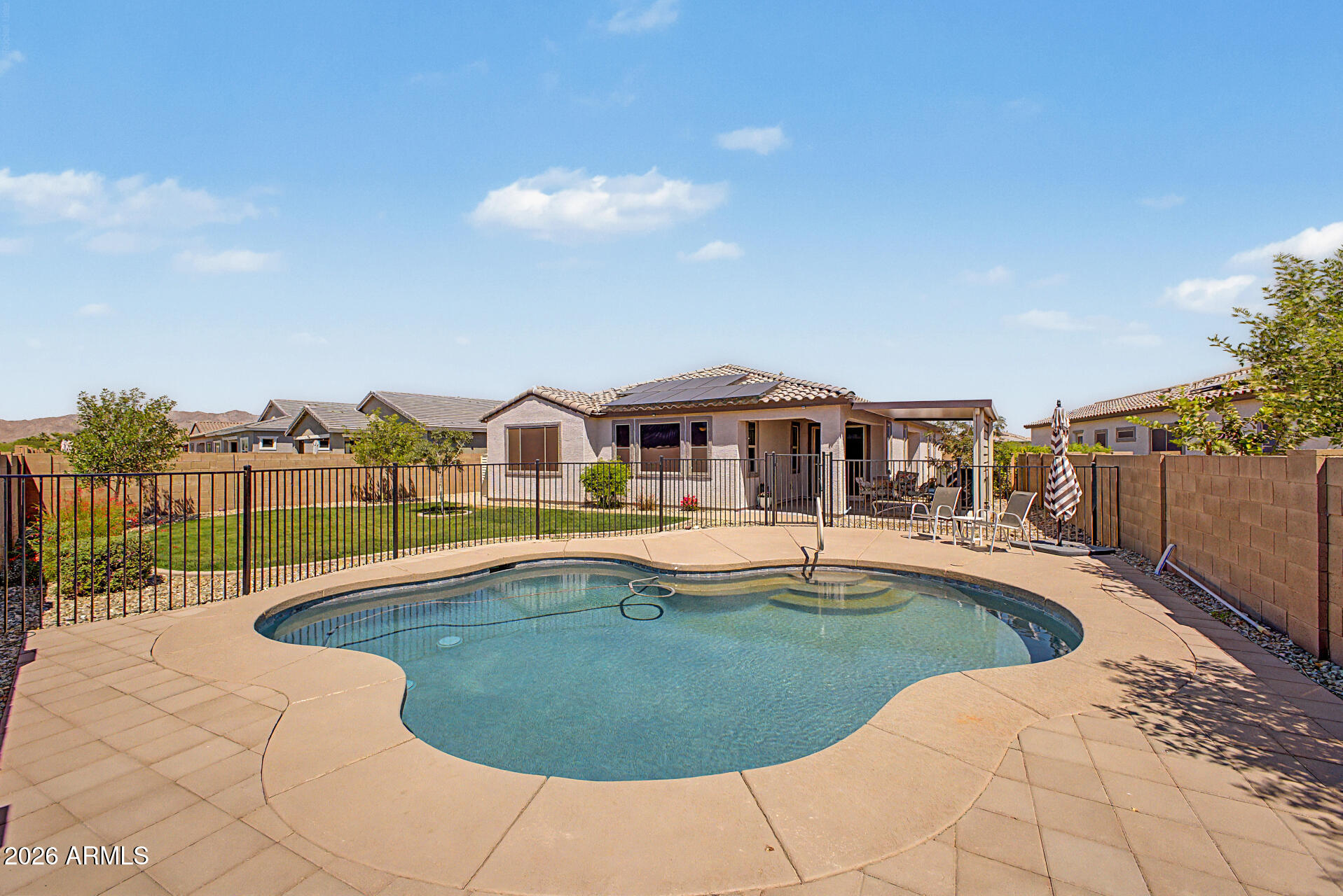 Live the Arizona dream in The Landings! Thoughtfully designed for the way you actually live, this stunning 4-bed, 3-bath split floorplan gives everyone their own space, including a luxurious primary suite w/ an oversized shower, dual sinks & oversized walk-in closet, plus a private guest ensuite. Cook and entertain in style w/ a chef's kitchen featuring a gas oven/range, quartz countertops, massive island w/ pendant lighting, pull-out shelves & an RO system. Tile in all the right places with hypoallergenic carpet in the bedrooms. Stay comfortable year-round with 3-zone climate control & energy-efficient shade screens. Outside your private oasis awaits! With an over-sized lot, real grass, a color-lit saltwater pool & extended covered patio, it's a place for golden-hour gatherings. The 2-car garage offers overhead storage and a tankless water heater. Close proximity to Loop 303, White Tank Mountains, grocery, and restaurants. This home is sure to please!