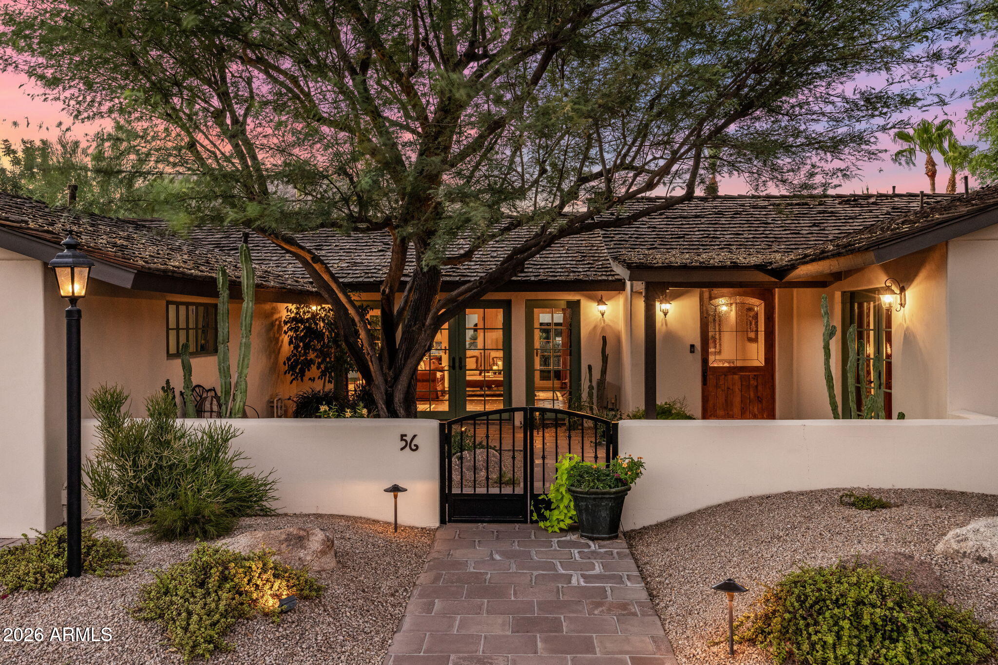 Mountain Shadows Estates East #56.  Desert Jewel Box in the Heart of Paradise Valley Warm elegance, timeless tradition, and classic Southwestern charm define this enchanting residence in the prestigious, guard-gated community of Mountain Shadows Estates East. Perfectly positioned between the iconic peaks of Mummy Mountain and Camelback Mountain, this exceptional Paradise Valley location offers an effortless lifestyle just moments from Mountain Shadows Resort, where fine dining, Executive golf course, and two spectacular resort pools await. A welcoming courtyard entry, adorned with blooming flowers, lush potted plants, a magnificent mesquite shade tree, and authentic Saltillo tile, creates a memorable first impression. The Saltillo flooring continues throughout the home, providing warmth, character, and seamless indoor-outdoor continuity. Designed for both comfortable living and gracious entertaining, the spacious great room features a cozy fireplace and a wall of French doors that open to the covered patio and beautifully maintained backyard. The adjoining dining area flows effortlessly into the inviting kitchen, complete with creamy custom cabinetry, a center island, butcher block countertops, and timeless finishes.  The thoughtfully designed floor plan includes a serene primary suite, a welcoming guest bedroom with sitting area and private access to the rear patio, and a distinguished gentleman's office featuring custom built-in bookshelves, elegant wainscoting, and French doors opening to the charming front courtyard.  The tranquil primary suite is a peaceful retreat dressed in soothing neutral tones and crisp whites, while the primary bath offers porcelain flooring and a dedicated vanity area. Outdoors, breathtaking Southwestern sunsets, mountain vistas, and views across the lush open green space create a picturesque backdrop for everyday living. This charming desert jewel box offers the perfect blend of privacy, beauty, and convenience in one of Paradise Valley's most coveted communities. Experience the effortless luxury, spectacular sunsets, and exceptional lifestyle that make Mountain Shadows Estates East so special.