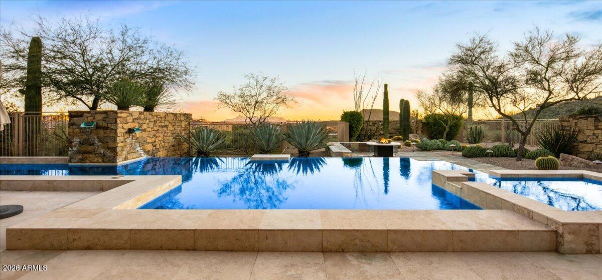 Experience refined desert living in this exceptional Desert Contemporary estate, located within the prestigious Desert Mountain community in the Village of Saguaro Forest. Spanning 6,242 square feet, this expansive residence offers 5 ensuite bedrooms, 5.5 baths, a private den, and a generously sized guest house complete with its own living room, full kitchen, and separate bedroom, providing ideal accommodations for extended stays or private hosting.
Designed for both grand entertaining and everyday luxury, the home features a fully equipped chef's kitchen with every modern amenity, including Sub Zero refrigerator, Wolf range with double ovens, plus  a wall oven, Miele built in coffee maker, dual dishwashers, extensive cabinetry and walk in pantry,  Additional highlights include a formal Dining room, a temperature controlled wine cellar, and a large wet bar perfectly positioned for effortless entertaining. A four car garage adds both convenience and functionality.
The resort style backyard is an entertainer's dream, showcasing a dramatic infinity edge pool and spa, outdoor fireplace, fire pit, expansive deck spaces, and a separate grill patio ideal for hosting gatherings under the desert sky. Enjoy sweeping views of city lights, surrounding mountains, and unforgettable Arizona sunsets, all from the privacy of this remarkable estate that truly embodies the best of Desert Mountain living. Contact DM Membership for additional information and wait times. 0.45% Capital Reserve Fund Fee will be charged on the purchase price of home paid by the buyer.