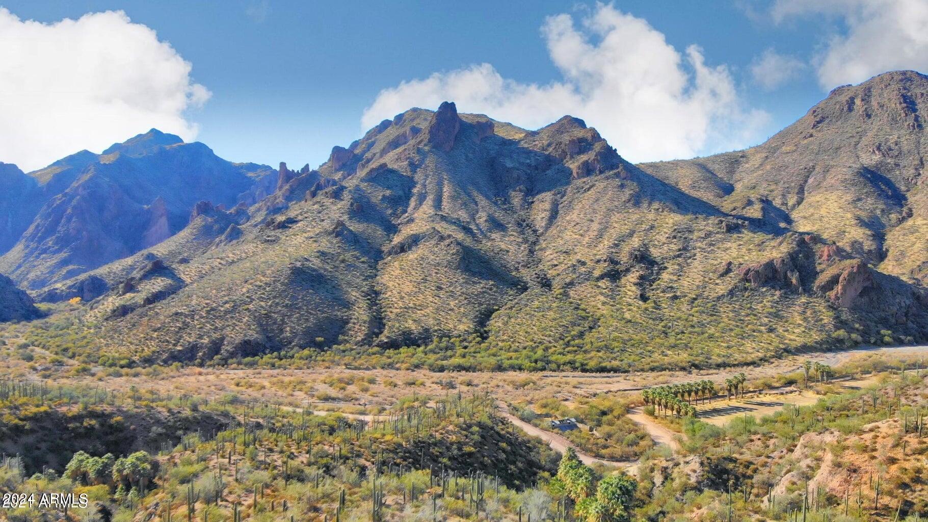 Welcome to your private oasis with natural springs, incredible mountain views and quality water supplied by private domestic well. Purchasing the historic JL Bar Ranch in 2022 for over $3 million & investing almost $2 million in rejuvenating the ranch. A new well that has ''hot'' water'', barn remodel (incomplete) electric upgrade & other improvements. The Owners vision has changed & they would like to offer the property w/393 acres to a Buyer to create their own private estate or??  The property is 8 parcels, 7 parcels are contiguous. This area is home to Castle Hot Springs Resort located a mile South of the property on a well-maintained dirt road. Castle Hot Springs is a boutique resort where adventure meets luxury in a verdant desert oasis. Look at Document section for more information