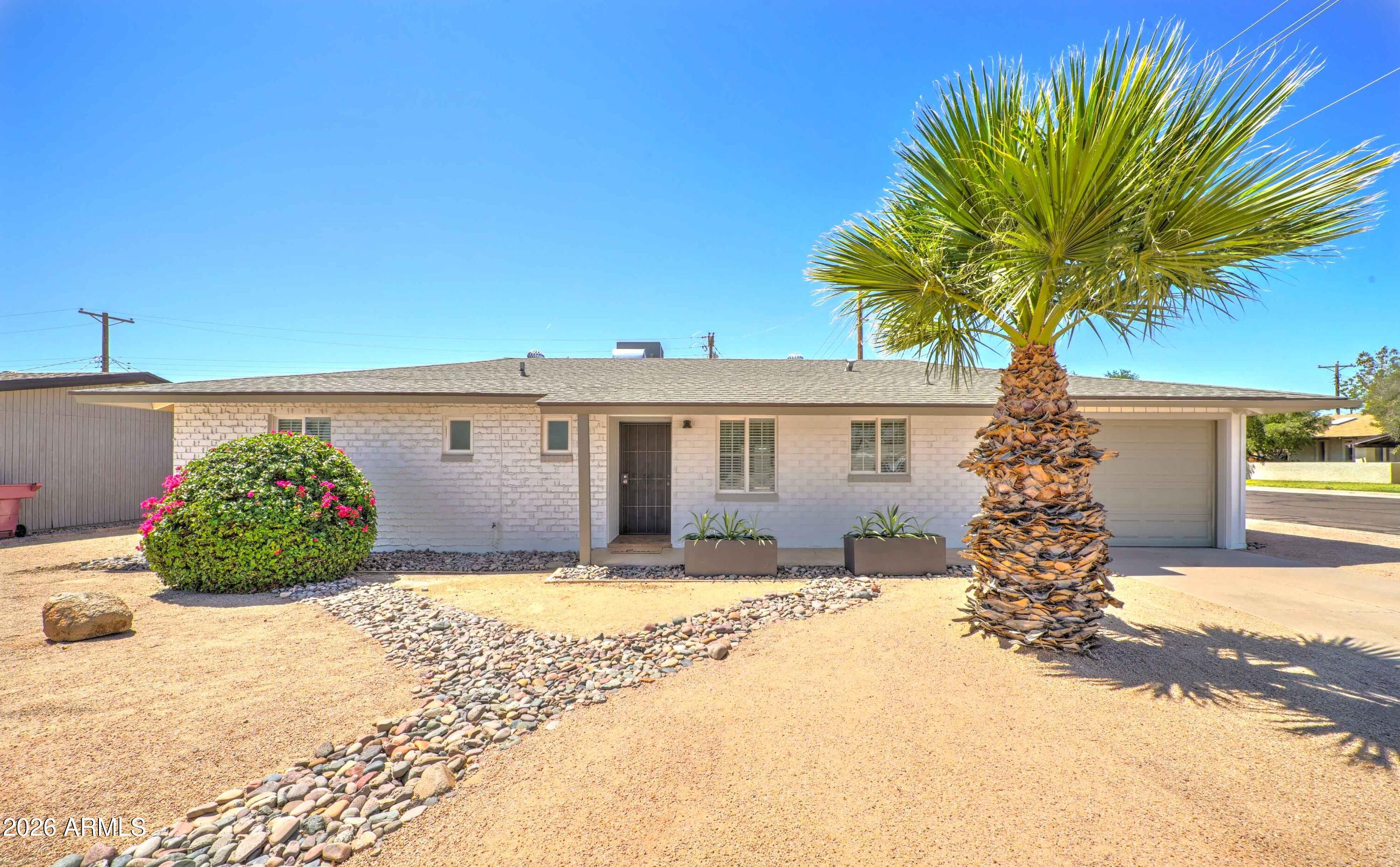 Located between Old Town Scottsdale and Arizona State University, and just minutes from Papago Park, Phoenix Zoo, and Desert Botanical Garden, this charming ranch-style home offers a fantastic location with easy access to dining, recreation, and entertainment. Situated on a desirable corner lot, the home features low-maintenance desert landscaping and inviting curb appeal.

Inside, the updated eat-in kitchen showcases a clean white and gray palette, ample cabinetry, and included appliances. Tile flooring runs throughout the home, complemented by dual-pane windows, ceiling fans, and abundant natural light. The spacious living area features French doors and a charming brick accent wall that adds warmth and character.

((CONTINUED)) The primary suite includes a remodeled en suite bath with a walk-in shower, while two additional bedrooms offer flexible space for guests, family, or a home office. Interior laundry with stackable washer and dryer adds everyday convenience.

Outside, enjoy a private backyard with an oversized paver patio, mature greenery, and plenty of space to relax or entertain.