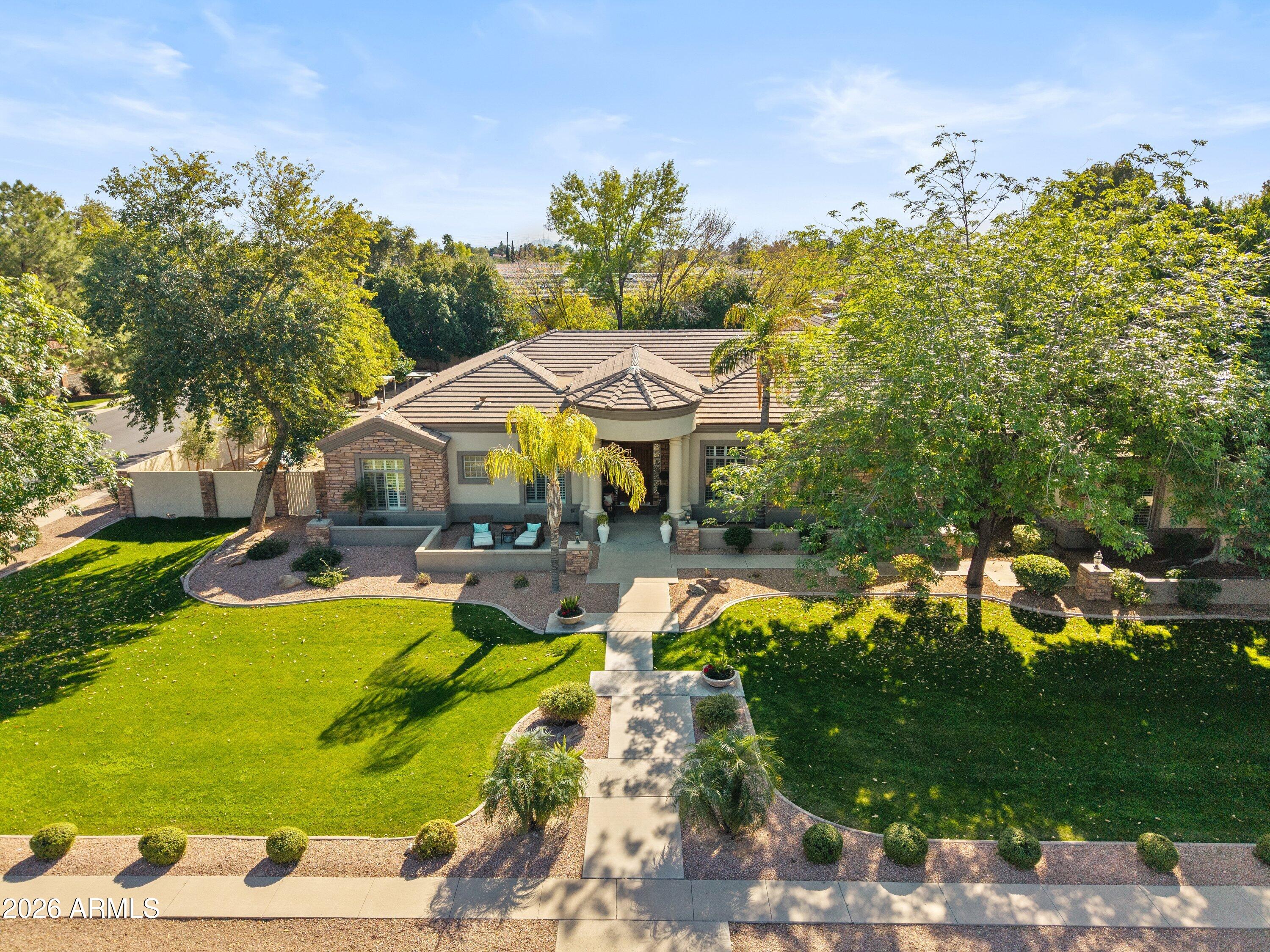 At first glance, it feels like you've arrived in a peaceful neighborhood far outside the city with mature trees, spacious lots and quiet surroundings. Walking the lushly landscaped streets of Somerset Estates, it's hard to believe you're actually in the heart of the city and close to everything. Set on a nearly one-acre corner lot, this beautiful custom home offers a rare blend of privacy, charm and convenience.
Major recent improvements include three new Trane 5-ton HVAC systems and a new main roof in 2023 along with a new water softener, spa and pool system upgrades completed in 2022, providing peace of mind and long-term value.
The home offers a highly functional and flexible layout with six bedrooms, four and a half bathrooms, dual primary suites, multiple living spaces and a dedicated office, making it ideal for multigenerational living, large families or those who love to entertain. Engineered hardwood flooring, detailed millwork, wainscoting, stone accents, beams and tray ceilings elevate the interior with warmth and architectural character throughout.
The open-concept kitchen features double-stacked custom white cabinetry with glass uppers, a quartz island, wall ovens and a gas cooktop, flowing seamlessly into an open living and dining area flooded with natural light.
Outdoor living is equally impressive with extensive covered patios, paver entertaining space a sparkling pool, fruit trees and lush lawns in both the front and back, all supported by grandfathered flood irrigation. The nearly one-acre lot offers exceptional space, privacy and natural tranquility rarely found in today's market.
Car enthusiasts, hobbyists and adventure lovers will appreciate the four-car garage plus an oversized RV garage approximately 34' deep and nearly 23' wide.
Homes in this tightly held neighborhood rarely come to market. This is a unique opportunity to own a timeless property in one of Mesa's most sought-after neighborhoods.