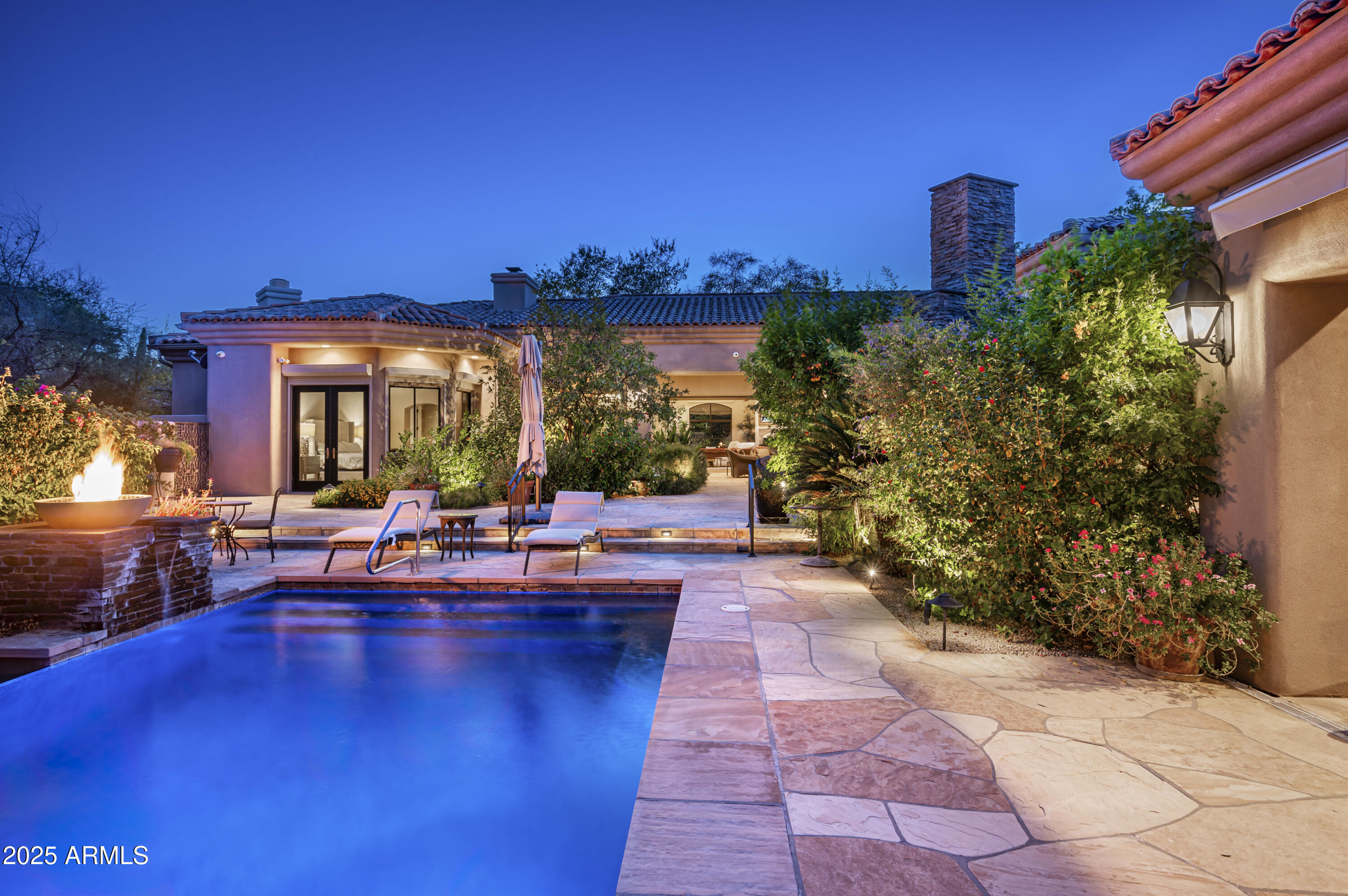 A rare opportunity to own in the exclusive gated community of Desert Jewel Estates in Paradise Valley. Tucked away at the end of a quiet cul-de-sac, this stunning estate offers unmatched privacy and space on just over an acre of lushly landscaped grounds. Spanning over 7,000 square feet, this exquisite home features 5 bedrooms and 5.5 bathrooms, including a detached guest casita—perfect for visitors or multi-generational living. Inside, expansive living and family rooms open seamlessly to the outdoors with automated, wall-pocketing sliding glass doors, creating a true indoor/outdoor lifestyle ideal for Arizona living. The backyard is a true retreat, boasting a sprawling covered patio, built-in BBQ area, exterior fireplace, and striking negative edge pool. Surrounded by lush, tropical-style landscaping, the setting feels like a hidden oasis in the desert both tranquil and breathtaking. Additional highlights include a temperature-controlled, extended-length 4-car garage, ideal for car enthusiasts or extra storage. Whether you're entertaining on a grand scale or enjoying a quiet evening under the stars, this home delivers elegance, comfort, and the perfect blend of indoor sophistication and outdoor serenity.