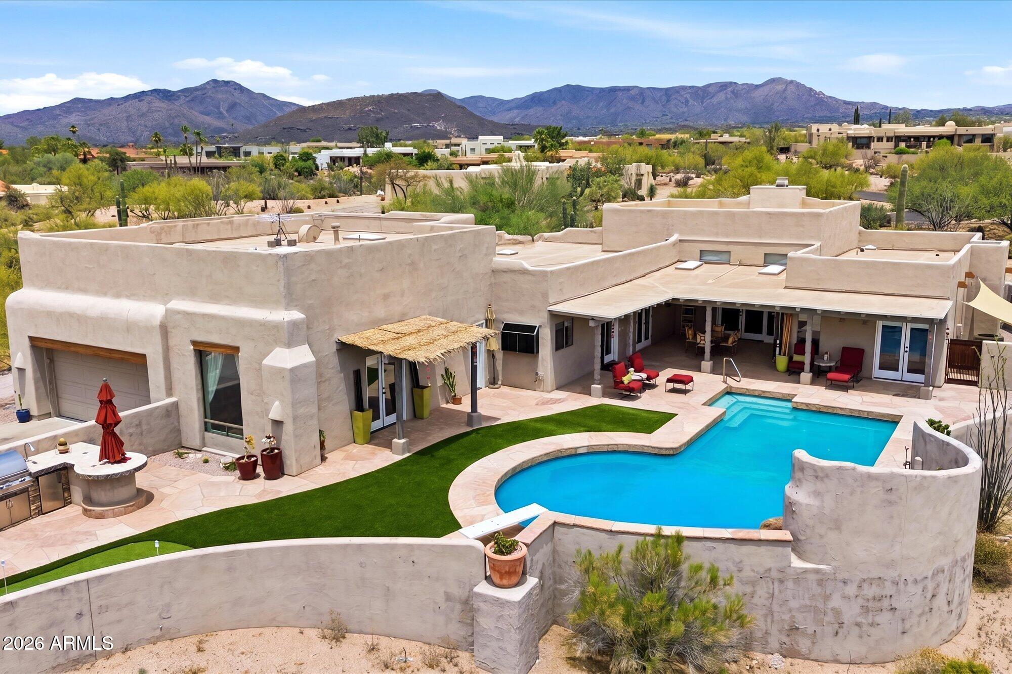Delightful custom Santa Fe home situated on an elevated acre in an upscale peaceful Carefree neighborhood surrounded by mature saguaros, xeriscape desert landscaping, and stunning mountain views, including iconic Black Mountain. This warm and inviting residence showcases travertine flooring, soaring 12-foot ceilings, beautiful wood and iron accents, decorative pot shelves, a wet bar, and exceptional indoor-outdoor living.
The chef's kitchen is designed for both entertaining and everyday living, featuring a Sub-Zero refrigerator, large island with seating for four, granite countertops, warming drawer, oven with convection/microwave combination, wine cooler, wine rack, glass-front cabinetry, kitchen desk, and abundant storage. An adjoining laundry room includes a utility sink and a walk-in pantry added convenience. The dining room boasts a wet bar, shelving and direct access to large covered patio. 
The thoughtfully designed floor plan offers three private bedroom suites, each with its own bathroom and generous walk-in closet. The luxurious primary suite features two walk-in closets and access to the back yard and spa, creating a true retreat. A spacious family room and dedicated pool bath provide additional ease of living.
Step outside to your resort-style backyard oasis, complete with an oversized diving pool, heated spa, multiple covered patios, built-in BBQ island with bar seating, putting green, flagstone patios, and numerous gathering areas designed to take full advantage of Arizona's spectacular weather and mountain views.
The extended two-car garage offers ample room for hobbies and storage, featuring a large air-conditioned workshop/storage room, a huge loft, extra ceiling height suitable for vehicle lifts, and convenient automatic bike lifts.
With extremely low HOA dues and a prime Carefree location close to championship golf, fine dining, shopping, hiking trails, and top-rated schools, this exceptional property offers the perfect blend of luxury, comfort, and Arizona lifestyle. A truly special home not to be missed.