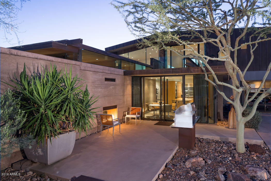 This extraordinary contemporary architectural marvel offers resort-style living at its finest. Located on a 2.5 acre private estate this AIA Citation Award Winning Home is a combination of modernist lines mixed with natural elements evidenced by a mix of 24” rammed earth walls, copper clad exteriors and finished concrete floors. This 6 bedroom, 6.5 bath home offers soaring 10’-21’ ceilings with walls of glass showcasing Camelback Mt. The gourmet eat-in kitchen includes Wolf appliances, 2 way fireplace, and honed Maderia Gold granite counters opening to an al fresco dining patio overlooking the pool. A luxurious master suite features a study, sitting room, 2 closets, fireplace and magnificent views. Further highlights include a media room, gated auto court, 3 car garage and attached casita.