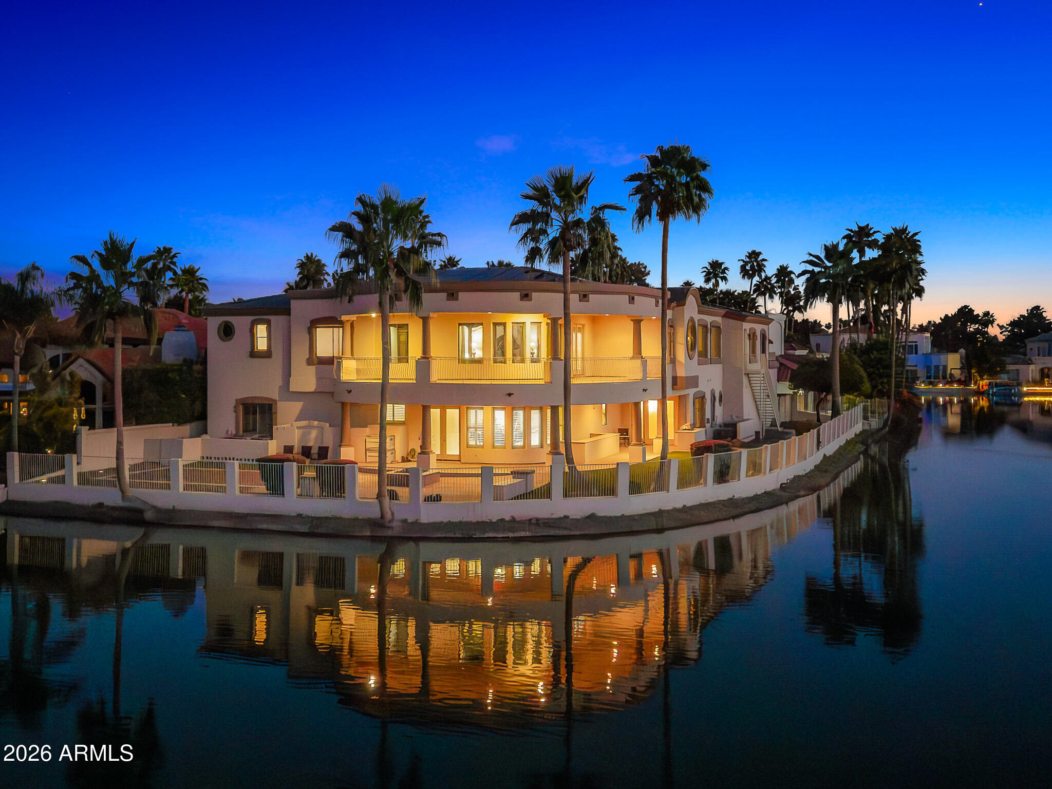 Experience a rare lakeside lifestyle in the desert within the gated community of West Lakes Estates. Tucked at the end of a quiet cul de sac, this timeless estate captures sweeping lake views and unforgettable Arizona sunsets, creating a truly picturesque setting. A grand staircase makes a striking first impression, setting the tone for the home's elegant interiors, including a formal dining room illuminated by a crystal chandelier. The spacious kitchen is designed for both beauty and function, featuring granite countertops, high end appliances, and an oversized island that flows seamlessly into the family room with a gas fireplace and soaring ceilings. A private home theater adds to the home's impressive amenities. The lower level is an entertainer's dream, complete with a secondary kitchen, expansive game room, 720 bottle wine room, private living quarters, and a fully equipped home gym.  Upstairs, five well appointed bedrooms plus an attached guest suite with its own kitchen and living area, ideal for extended stays or multi generational living. The primary suite is both grand and inviting, featuring a charming sitting room overlooking the lake, a spacious walk in closet, dual vanities, a jetted soaking tub, and a walk in shower. Residents enjoy access to community amenities including pickleball and tennis courts, all while being ideally located in one of Gilbert's most sought after neighborhoods. This is a rare opportunity to enjoy refined, resort style living with a lakeside backdrop in the heart of the desert.