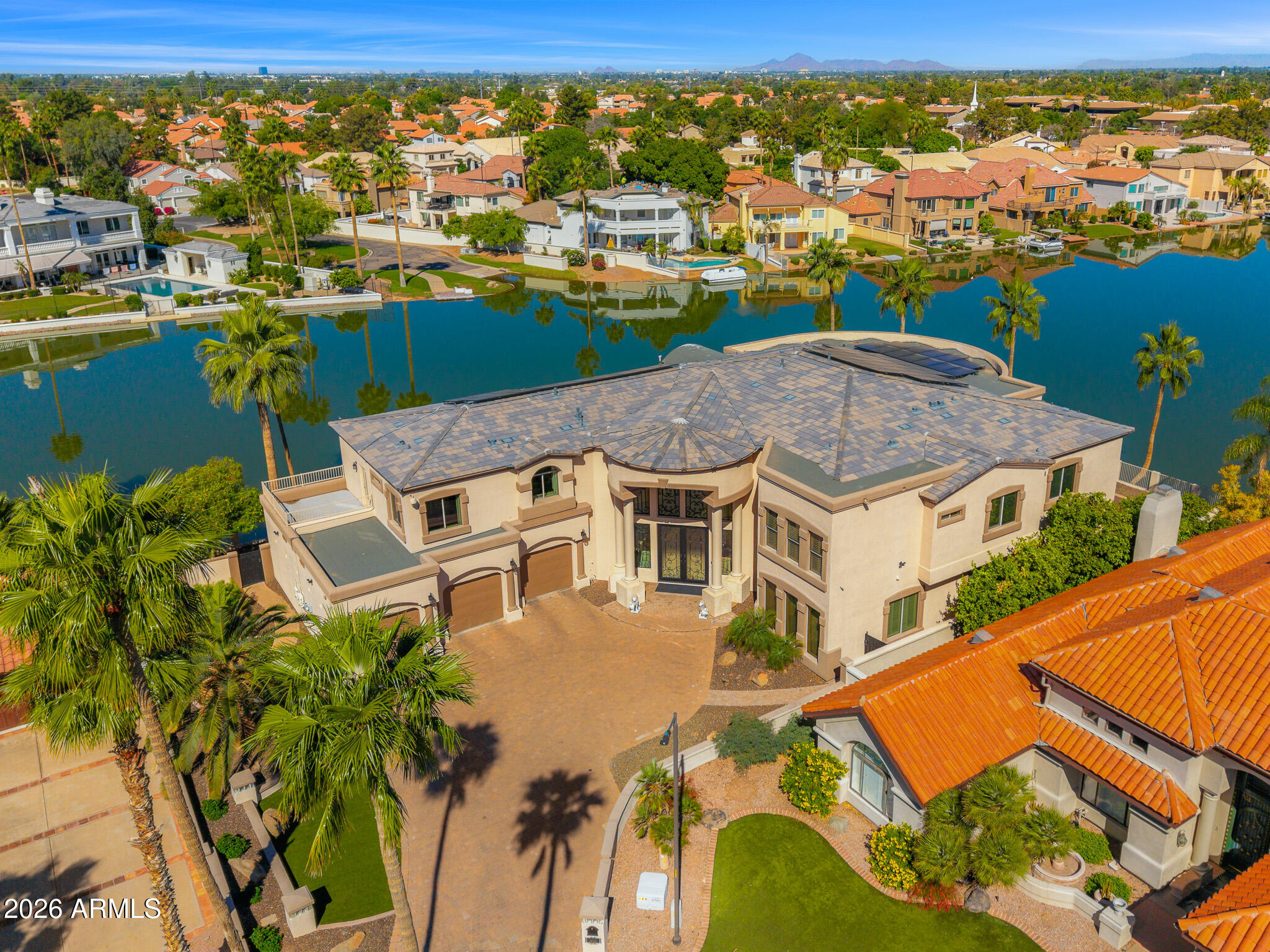 Experience a rare lakeside lifestyle in the desert within the gated community of West Lakes Estates. Tucked at the end of a quiet cul de sac, this timeless estate captures sweeping lake views and unforgettable Arizona sunsets, creating a truly picturesque setting. A grand staircase makes a striking first impression, setting the tone for the home's elegant interiors, including a formal dining room illuminated by a crystal chandelier. The spacious kitchen is designed for both beauty and function, featuring granite countertops, high end appliances, and an oversized island that flows seamlessly into the family room with a gas fireplace and soaring ceilings. A private home theater adds to the home's impressive amenities. The lower level is an entertainer's dream, complete with a secondary kitchen, expansive game room, 720 bottle wine room, private living quarters, and a fully equipped home gym.  Upstairs, five well appointed bedrooms plus an attached guest suite with its own kitchen and living area, ideal for extended stays or multi generational living. The primary suite is both grand and inviting, featuring a charming sitting room overlooking the lake, a spacious walk in closet, dual vanities, a jetted soaking tub, and a walk in shower. Residents enjoy access to community amenities including pickleball and tennis courts, all while being ideally located in one of Gilbert's most sought after neighborhoods. This is a rare opportunity to enjoy refined, resort style living with a lakeside backdrop in the heart of the desert.