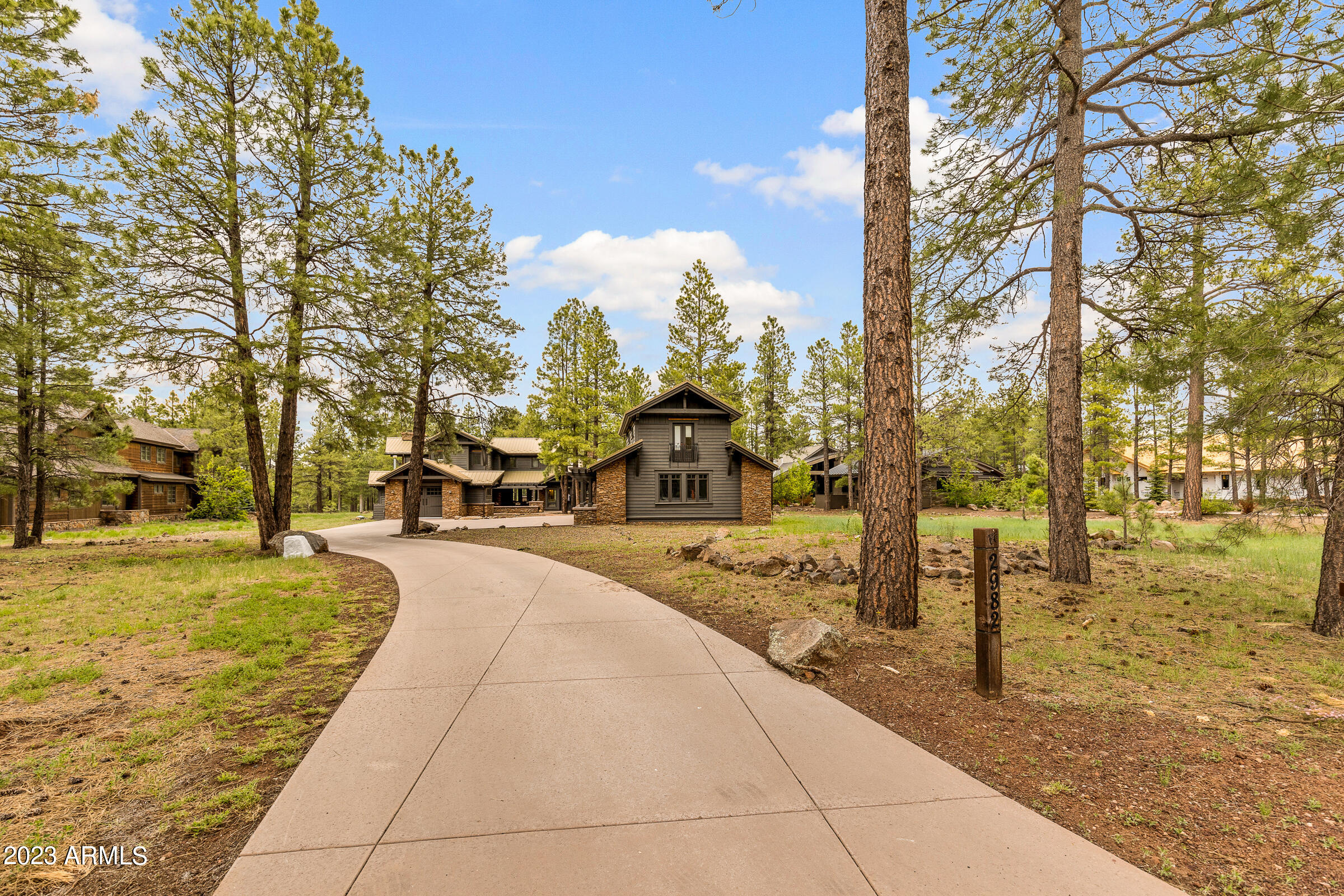 One-of-a-kind custom home in Forest Highlands with golf course views.  The home is set back on a near-acre lot, with a separate guest house! Appointed throughout with unique windows, crafted iron hardware, stone flooring and numerous cozy nooks both within and outside the home.  The eat-in chef's kitchen is spectacular with an adjacent den and a more formal dining area. The fireplaces in the living spaces are perfect for relaxing during the cool mountain nights.  With an attached, garage, as well as a detached 2-car garage beneath the guest house, there is ample space for toys and guests. In addition to the 4 bedrooms of the main house, you'll find a library/den, office adjacent to main level master suite, and another family room upstairs. The home is a short walk to the Meadow Clubhouse.