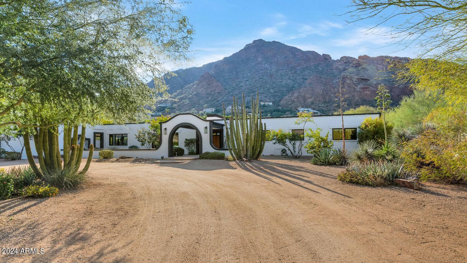 Newly remodeled Primary Bath! The perfect fusion of Modern and Mexican Territorial, this exceptional Paradise Valley home is both sleek and charming! The 9' beamed ceilings accent the open kitchen/family room concept and the floor plan is ideal for large and small gatherings. Sitting on almost an acre at base of Camelback Mountain, the views are incredible and the outdoor spaces capture the essence of desert living at its finest. The Primary Retreat is a sanctuary with a new bathroom, fireplace, sitting area, outdoor shower and private firepit perfect for sunset views. A newly remodeled Guest House features 2 bedrooms, 1 bath, full Kitchen and Living Room and looks over the resort-style backyard including pool, hot tub, grotto waterfall, outdoor fireplace, pickleball court, and low-maintenance turf. In addition to the gym, enjoy a bonus room with built-in shelves perfect for office, tv or flex bedroom (with a closet). Truly one of the most uniquely beautiful properties in Paradise Valley!