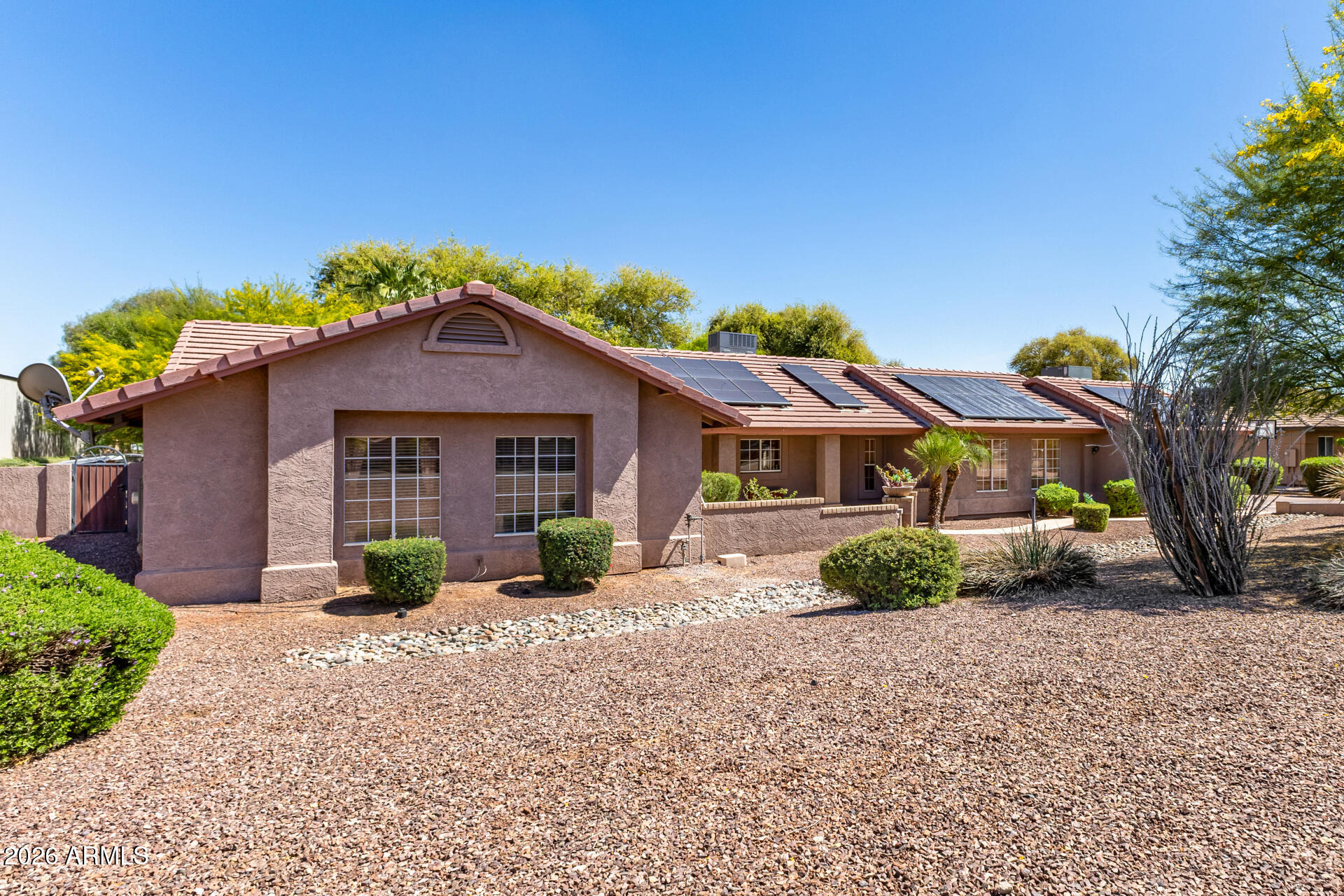 This single level home is situated on over  an acre of lush green grass, and trees with a sparkling fenced pool surrounded by palm trees - your own private oasis.. The home features open expansive living spaces with a living room, family room and an Arizona room, you have lots of options for formal or casual living.
The open kitchen is an inviting space to prep, cook and gather around the large island. Granite countertops, stainless steel appliances and plenty of cabinet space. 
There is room for all your toys or hobbies in the detached garages. 2 car garage in front and a single car garage in the rear of property that would be a perfect shop or maybe a great ''mancave'' /''she shed'' with both water and electric.
Grass is watered through flood irrigation 
Chickens and horses are welco