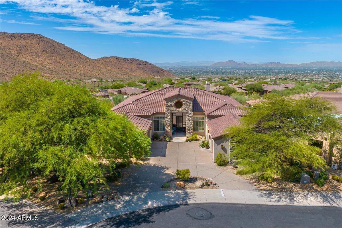 Nestled within highly sought-after McDowell Mountain Ranch. This stunning home with magnificent mountain and city light views sits on a generous, elevated, cul-de-lac lot in the prestigious 24 hour gated community of Cimmaron Ridge (Hills). As you step through the entrance, you are welcomed by an impressive circular foyer adorned with elegant stone accents, setting the tone for the luxury that awaits. The main living room, featuring a striking stacked stone fireplace, seamlessly flows into the formal dining area, which is graced by a  wall of windows framing breathtaking mountain views. Throughout the home, travertine flooring adds a touch of timeless sophistication. The gourmet kitchen has been meticulously remodeled, boasting pristine white cabinetry, gorgeous stone countertops, stainless steel appliances, a Sub-Zero refrigerator and freezer, new dual ovens, a 6-burner gas range, convenient pull-out drawers, and a central island that opens to the expansive great room. Here, you will find another inviting fireplace with designer tile surround, along with a custom-built entertainment center complete with a wine fridge and beverage fridgeperfect for entertaining. The primary suite is a true sanctuary, featuring wood shutters, a spa-like remodeled bath, and dual walk-in closet with custom built-ins and a shower with multiple shower heads and body jets. All additional bedrooms are generously appointed, with the flexibility of an office that could serve as a fifth bedroom, a separate bonus room, and private guest quarters with their own entry. Outside, the resort-style backyard is nothing short of spectacular, offering expansive city light and mountain views. Enjoy the luxurious infinity-edge pool and spa with cascading rock water features, practice your swing on the putting green, or entertain with a built-in BBQ and built-in firepit area with built-in seating. Enjoy all the additional community amenities that include, multiple heated pools, tennis and pickleball courts, a work-out facility, children's playground with splash pad and miles of scenic hiking trails. Call us today to schedule your private showing.