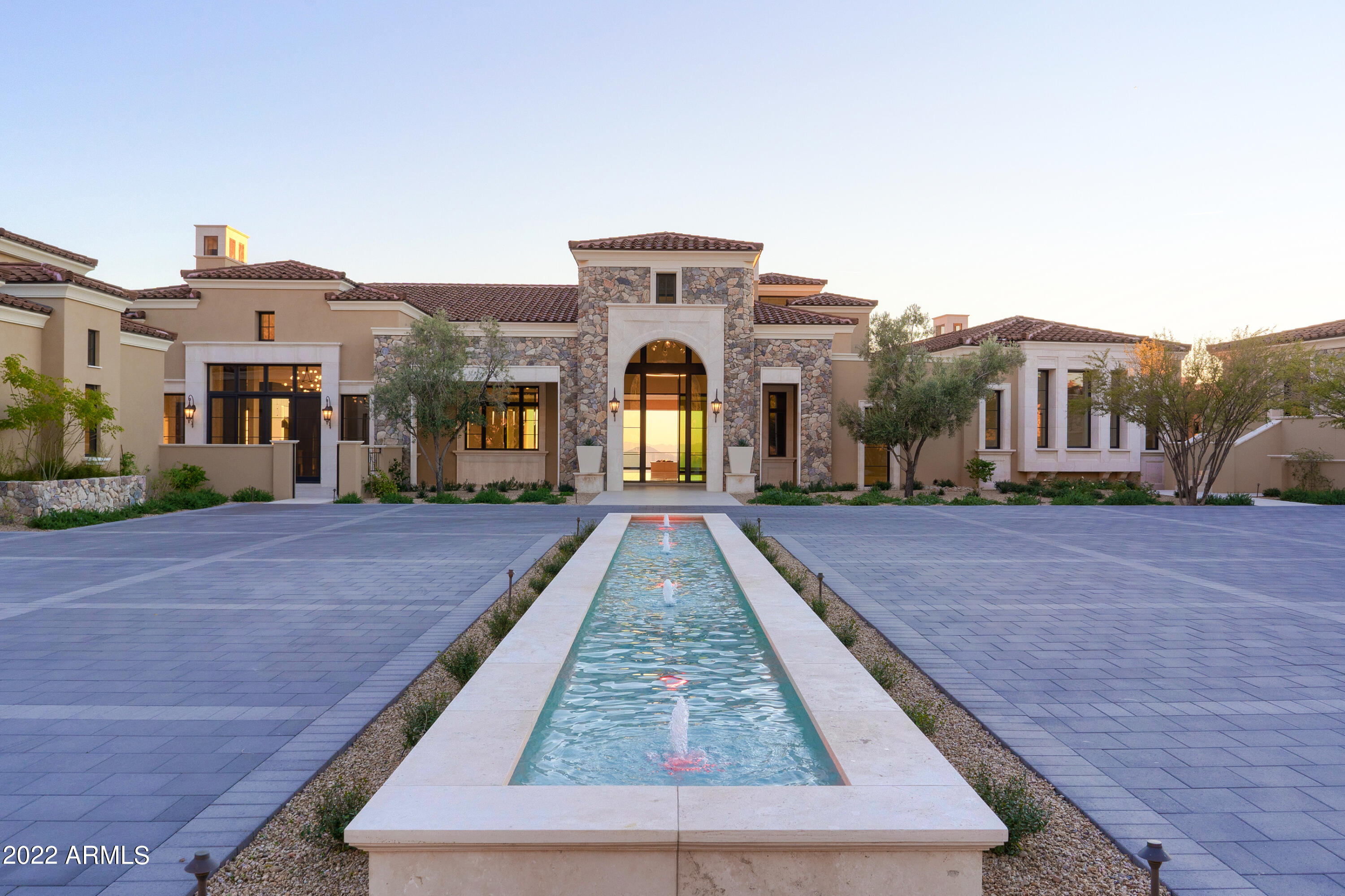 Exquisite modern elegance meets raw desert beauty in this one-of-a-kind Scottsdale estate, Altitude at Silverleaf, newly constructed in 2021 by Mast Luxury Homes. Located on the most prominent peak in the prestigious Summit at Silverleaf community & sitting on nearly five acres, city & desert views abound from every interior room & generous outdoor space. The privately gated, circular driveway provides a resort-style welcome that leads to a stunning mountain backdrop, complete w/an elevated, covered viewing tower to fully take in the McDowell Sonoran Preserve's majesty.
Once inside, incredibly high ceilings give way to 3 levels of remarkable finishes, including extensive use of imported natural stone with a special focus on marble and natural quartzite and 5 natural stone fireplac This Dale Gardon-designed home is a space fit for hosting the
grandest of gatherings, with an open floor plan meant for mingling. The spacious, custom entryway wine bar shines as a bright and unique welcoming point into the 8 ensuite bedrooms,
12 full baths, and 6 half-baths, with easy elevator access between each floor.  Natural light pours beautifully into the kitchen, with Subzero/Wolf appliances, including a Wolf Convection Steam Oven and 60" Wolf Range with two ovens, ideal for entertaining large parties year-round. The double islands are topped with the finest Quarzo Iceberg Natural Quartzite imported from Italy and equipped with warm under-lighting to enhance the inviting environment. Remarkable modern lighting fixtures float above the breakfast and coffee bar, and serve as stylish art pieces of their own throughout this Control4 smart home. Opulent comfort is the theme in every room, and is especially found in the exercise room with its steam shower and the yoga/art room with panoramic views. The cards and game room offers endless opportunities for enjoyment, with two Subzero wine columns waiting for a collection fit to age and share throughout the years. For those seeking a retreat into their favorite films, the theater with a 4K projector and professional sound system makes going to the movies as simple as dimming the lights at home and sitting back with the family. The Primary Suite is yet another stunning escape, with his and hers walk-in closets and an ensuite bathroom befitting the finest hotels in Europe. Italian-imported Calacutta gold marble
adorns the Primary Bath, which also includes double-sinks, a bidet, and his and hers water closets. When work is at hand, the office is the perfect quiet space to engage the mind, with
spectacular inlaid walnut ceilings and a powder room for easy access throughout the day. In addition to providing a resplendent place for anyone to call home, this estate is also outfitted
with multiple spacious and luxurious guest quarters. The guest casita ensures true privacy, with its own full kitchen and two ensuite bedrooms. There are also separate "in law" quarters with a full kitchen and ensuite bedroom, so the entire extended family can gather on a vacation of their own. Of course, when it comes time to bring everyone together, there is no better space than
the family room, which boasts accordion folding windows overlooking the palatial pool deck. It's well known that Scottsdale is made for year-round outdoor living, and this home was built
with that splendid lifestyle always in mind. Three outdoor fire pits overlook the city of Scottsdale, and even as far as the iconic Camelback Mountain in Phoenix. The two built-in grills make for
the perfect opportunity to show off new and classic recipes to gatherings large and small, and everyone will surely feel pampered at the infinity-edge pool with its cool, clear waters and
delicate fountain features. This is also a collector car lover's paradise, with the temperature-controlled 12-car garage and its own separate full bathroom offering a grand space
in which to house the most precious of vehicles.
This is truly the finest of neighborhoods in the Valley of the Sun, and beyond the private gates of this estate are some of the best opportunities for dining, shopping, and taking in scenic views
within only a few miles. Situated approximately 20 minutes from the exclusive Scottsdale Airpark and just a quick drive down the 101 freeway to the art galleries and designer shops in Old Town
Scottsdale, this is a location that cannot be rivaled.
Closer to home, the Silverleaf community includes its own astonishing amenities, and is particularly well-known for its extensive biking and walking paths, Tom Weiskopf-designed golf
course, and its glorious clubhouse and spa. For families seeking the best in education, this home is also located within the acclaimed Scottsdale Unified School District, home to Chaparral
High School and Copper Ridge Elementary and Junior High schools. Paradise is built and waiting at Altitude at Silverleaf for those who seek it, ready for a glorious new chapter to unfold in the life of its lucky owners.