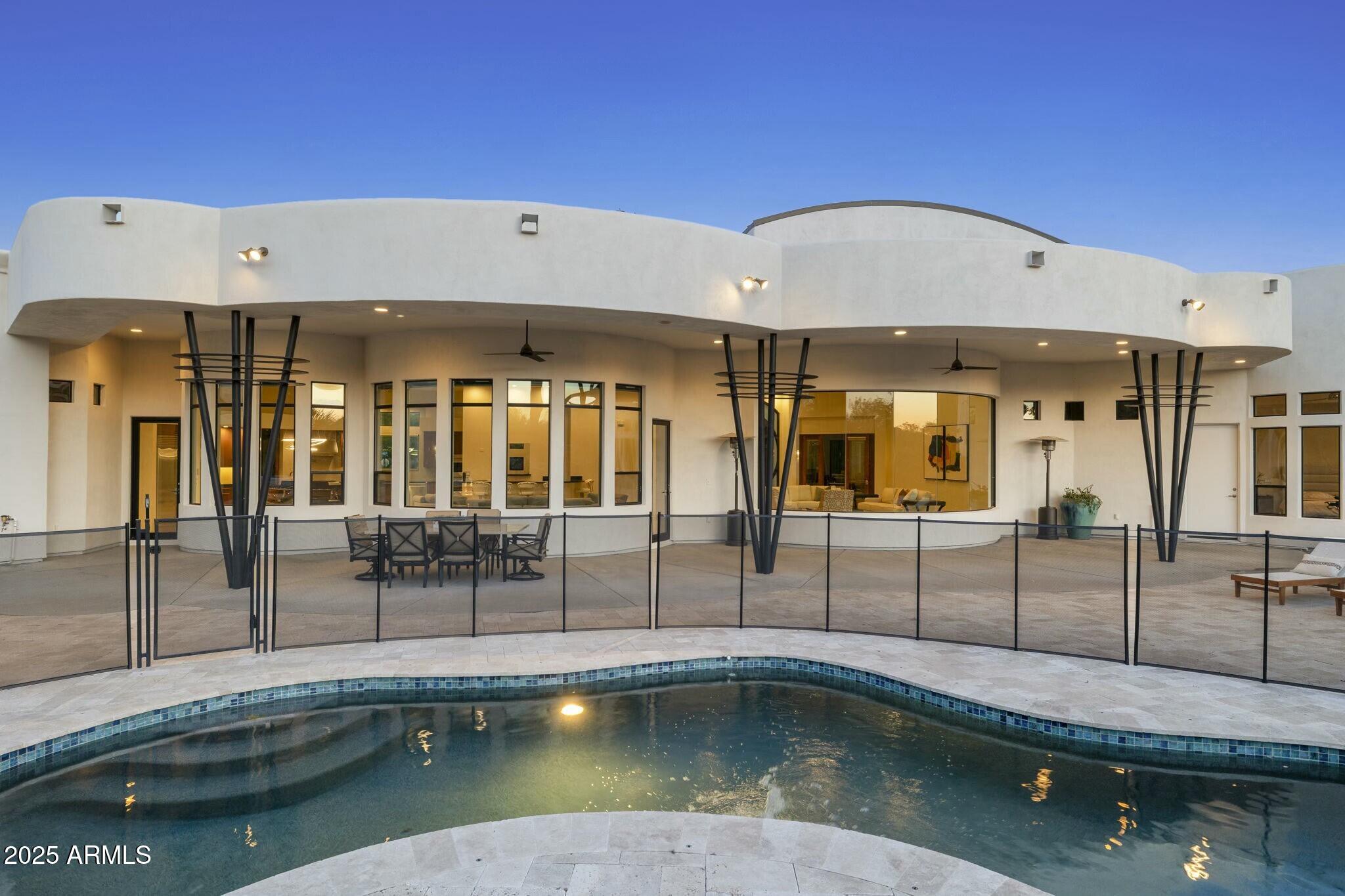 This single-level, contemporary Paradise Valley estate situated at the base of Mummy Mountain was thoughtfully designed by award winning architect, Nick Tsontakis, for easy living and entertaining.

The 5614 sqft home features 4 spacious bedrooms, an office, a large bonus room, 7 bathrooms, 2 laundry rooms, and a 4 car garage. It sits on 1.05 acres of flat, mountain adjacent land and is positioned ideally to maximize views from every room. Upon entering the custom 12 ft iron front door, 20+ ft ceilings and panoramic windows showcase the resort-style backyard. The office and formal dining are on either side of the entry and each have massive, curved windows giving natural light and views.

A temp controlled 300+ bottle glass wine wall by Heritage Vine and double-sided fireplace create a seamless flow from the formal living room into the open great living area. A chef's kitchen with Subzero and Wolf Appliances, walk-in pantry, and large island with seating for 4-5 opens to the generously sized family room, dining nook and wet bar to create an ideal area for easy entertaining. Two powder rooms flank the home's center and a butler's pantry with second dishwasher connects the kitchen and dining. All bedrooms are ensuite with walk-in closet. The Master has 2 generous closets, a second laundry room, walk through shower, jet tub, and backyard access.

The backyard features a large covered patio, open travertine and grassy areas with Phoenix Mountain Preserve views, a built-in gas fire pit, gas grill, mini fridge and outdoor bar seating. The swimming pool has a water feature and removable pool fence. There is a full outdoor bathroom with shower, RV gate and access to the 4 car garage. There is room to accommodate an addition, expand the garage, build a guest house or enjoy as is. 

PV is centrally located, 20 min from the airport and close to the valley's best dining, shopping, golf, resorts and schools.
