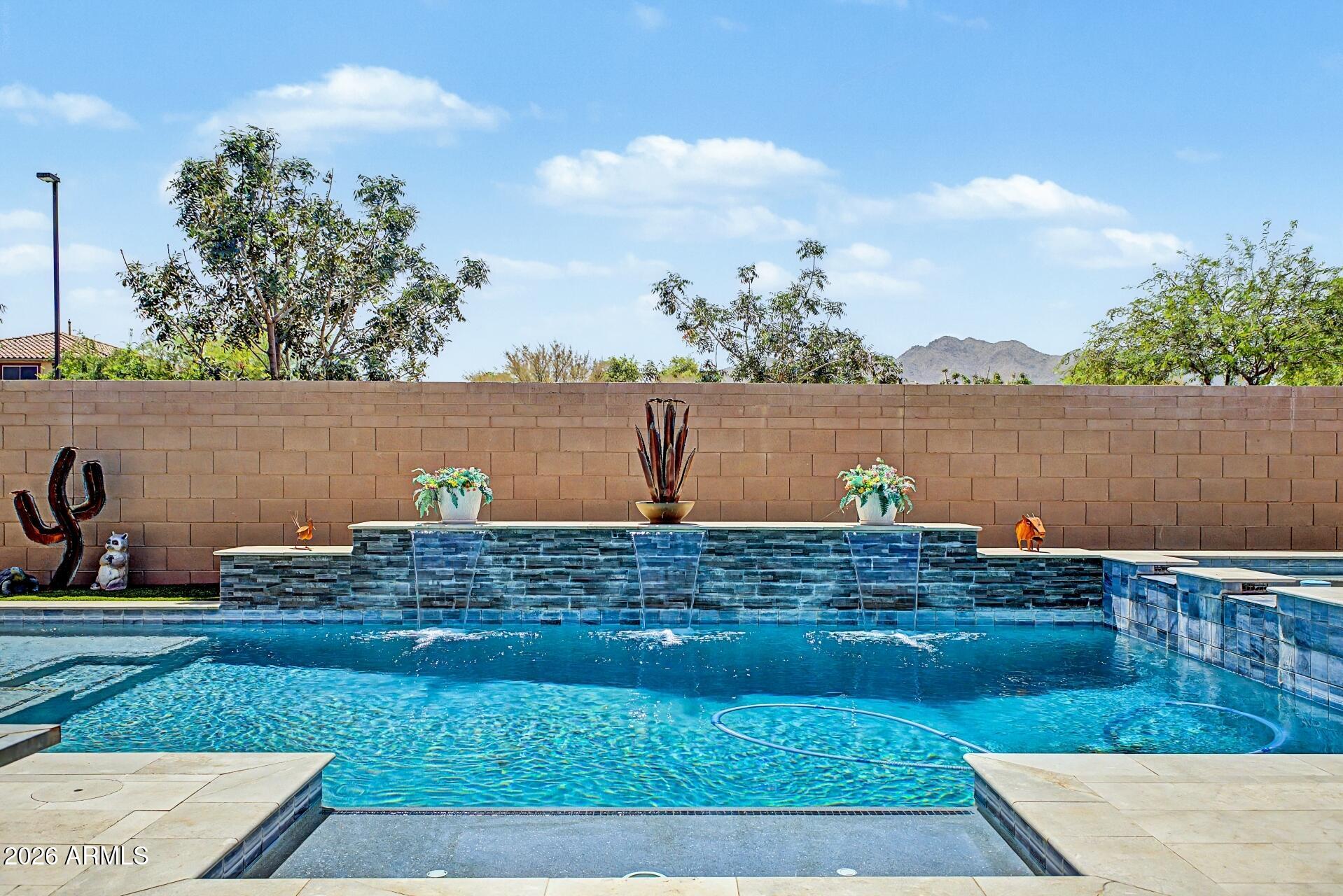 Welcome to luxury living designed for everyday comfort in the highly coveted Preserve in Adora Trails. This exceptional LEED & Energy Star Certified home offers the perfect blend of elegance, efficiency & thoughtful design.
Soaring 12-foot ceilings elevate the great room, kitchen, dining room, primary suite & bathroom, w/ 10-foot ceilings throughout the remainder of the home creating an open, airy feel from the moment you enter.
The chef's kitchen is both beautiful & highly functional, featuring upper cabinet extensions, extensive cabinetry & countertop space, an oversized island, spacious walk-in pantry w/ appliance outlet, Monogram Sub-Zero refrigerator/freezer, GE Profile gas cooktop w/ double ovens, & an over-counter microwave perfectly positioned above the coffee nook.
The seamless indoor-outdoor living experience is highlighted by an expansive 16-foot center-opening glass slider showcasing breathtaking unobstructed Mountain views. Step outside to your private backyard oasis complete w/ heated pool & spa, travertine pool decking, oversized covered patio w/ retractable power sunshade, misting system, three ceiling fans, artificial turf & a putting green, perfect for your short game. 
Boasting a desirable split floor plan w/ 4 spacious bedrooms, 3.5 bathrooms, custom wood accent walls throughout & a custom barn door in the primary bedroom, this home was crafted for both privacy & entertaining. One of the secondary bedrooms features its own ensuite full bathroom, while every bedroom offers generous walk-in closets.
The spacious bonus room offers incredible flexibility to fit your lifestyle. Whether used as a playroom, second living area, home gym, media room, game room, or movie theater, this versatile space provides endless possibilities.
A private functional courtyard welcomes you through a stunning custom iron security door. Inside, designer touches include plantation shutters throughout, even in the garage! 
Additional upgrades include epoxy garage floors, custom deep garage cabinetry, EV charging port, Polaris UV whole-home water filtration & soft water system, Ring cameras, Simply Safe security system, & conservative irrigated front yard landscaping.
This is more than a home, it's a luxury lifestyle. 
Preserve homeowners enjoy full access to everything Adora Trails has to offer, including the community clubhouse, resort-style pool w/ lap lanes & splash pad, just remodeled fitness center w/ studio room offering live fitness classes, full gym, scenic catch & release lake w/ fountains, many parks, playgrounds, basketball courts, walking and biking trails, on site elementary school, weekly food trucks, & year-round community events. All included in your low monthly hoa fee. The clubhouse & lake are just a short .3-mile walk away, perfect for morning strolls, sunset walks, fitness classes, neighborhood events, or simply unwinding by the water. This unique combination creates a lifestyle that blends elevated living w/ the convenience & connection of a vibrant master-planned community.
Residents enjoy convenient access to scenic hiking trails,  restaurants & shopping, & the expansive Gilbert Regional Park which has pickleball courts, a splash pad, playgrounds, & recreational fields. The community is also located near middle & high schools, making everyday living both convenient & connected.