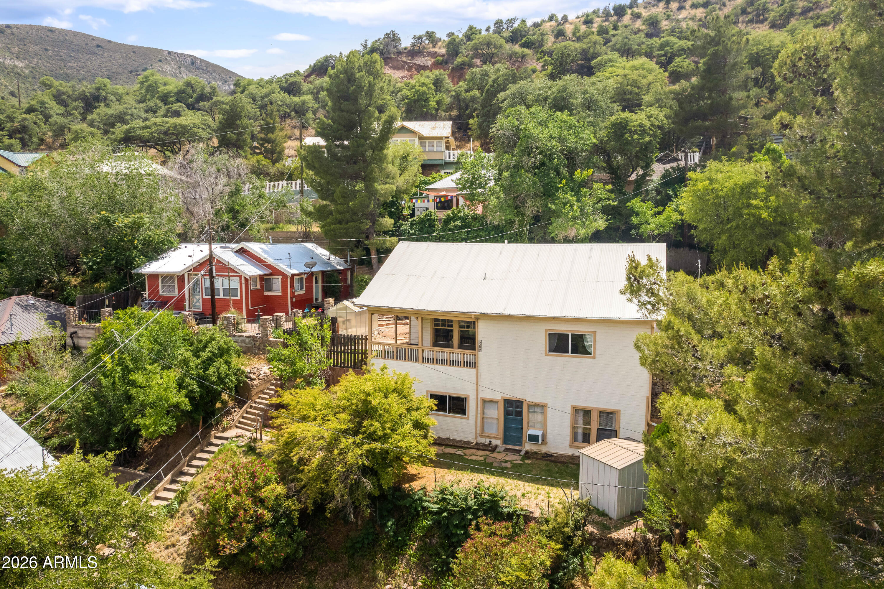 Historic 4bed/3bath 2,400 Sqft home perched in the heart of Old Bisbee with stunning views throughout & only moments from downtown. The top floor plan has been reworked to optimize functionality, has upgraded HVAC, sliding door added in the dining room, & much more. Both floors offer a full kitchen, living/dining space, laundry, pantry, private access, & 2022 hot water heaters. Downstairs includes new carpet in the bedroom, new gas heater, & separate yard. Outside offers a custom stone vineyard including 3 rows of established grape vines, flagstone walkways, greenhouse, storage shed, & rainwater catchment. This property is ideal for a large or multi-generational family, guest quarters or rental potential. Drawings to add spiral staircase included with sale. See video tour.
