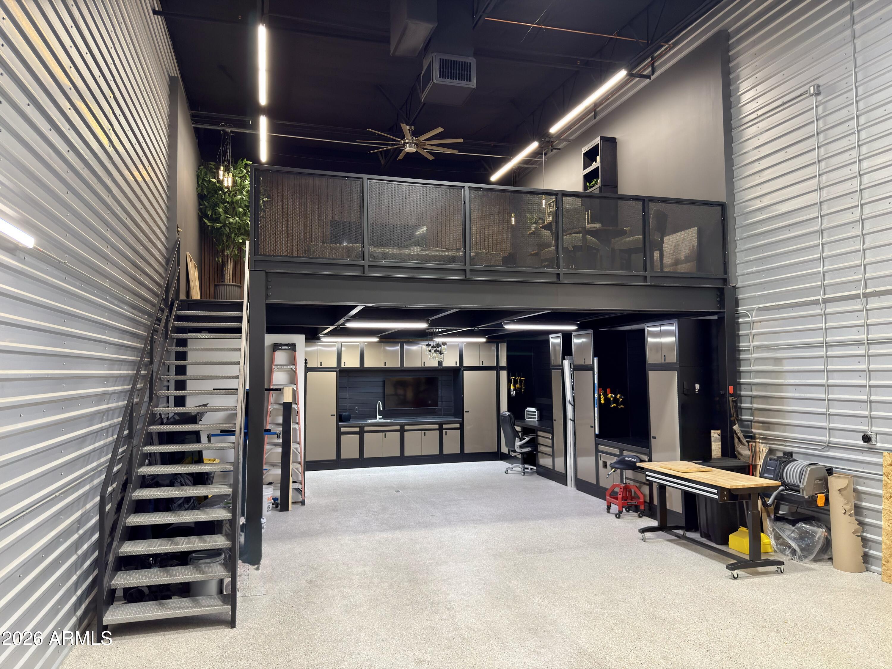 Extensively renovated and thoughtfully designed, this luxury Toy Barn combines high-end vehicle and recreational storage with a fully finished entertaining space, executive workspace, and upscale mezzanine loft. The main level features a new epoxy floor, custom cabinetry, built-in work areas, upgraded lighting, premium hardware, and abundant storage. The custom mezzanine includes wood-style flooring, designer accent walls, a dramatic wood-slat media wall, oversized TV, custom cabinets, granite surfaces, distinctive live-edge countertops, dining space, and a comfortable lounge area. Additional features include a kitchenette-style entertaining area with refrigerator and freezer, multiple TVs, Sonos audio throughout, Wi-Fi, air conditioning, and a beautifully renovated full bathroom. Freshly painted and loaded with upgrades, this move-in-ready unit is ideal for a car collection, recreational vehicles, workshop space, private retreat, or entertaining. One of the most impressive and luxurious Toy Barn units you will find.