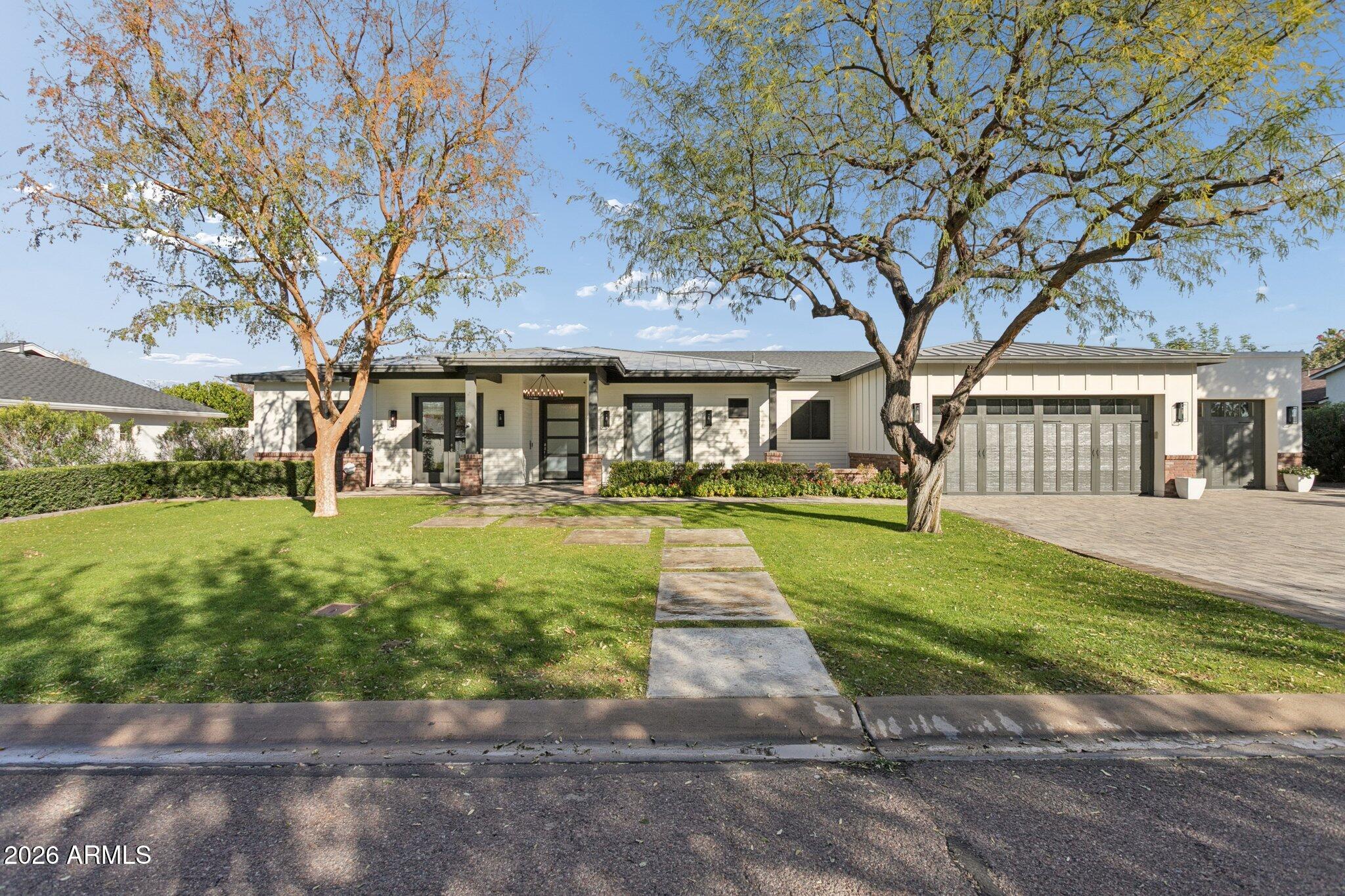 Exquisitely crafted in 2017, this open-concept home offers 4 bedrooms, 4.5 baths, a playroom, office, and an extended 3-car garage. Interior highlights include European Oak hardwood floors, contemporary fireplaces, custom built-ins, detailed wainscoting, and trim work. Situated on a half-acre North/South lot, the outdoor space features a shaded patio, built-in speakers, citrus trees, regulation bocce court, ramada with misters, heated saltwater pool and spa, grassy play area, and poolside basketball hoop. The chef's kitchen impresses with a large quartz island, Thermador appliances, farmhouse sink, wine cooler, beverage drawer, and walk-in pantry. Nestled on a picturesque street in one of Phoenix's most sought-after neighborhoods, this home offers a rare blend of style and comfort.