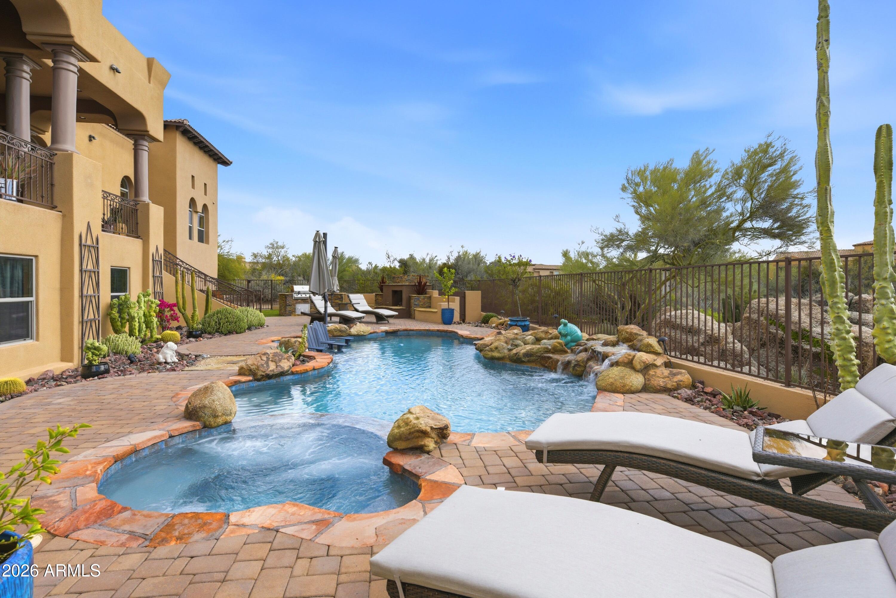 Elevated luxury in a private desert sanctuary. Nestled on an expansive 1.1-acre lot that borders a protected natural wash and pristine desert preserve. This 7,315-square-foot estate offers a rare master class in elegance and privacy. This home features 5 bedrooms, each with its own ensuite bathroom, and 2 separate half bathrooms. The heart of the home is a gourmet chef's kitchen, where functionality meets timeless craftsmanship. Fantastic home for entertaining with plenty of space for guests. The lower level could easily accommodate out-of-town visitors or even serve as a multi-generational living area. Rich alder cabinetry and expansive granite countertops are complemented by professional-grade stainless steel appliances, creating an environment that is as practical as it is beautiful. Adjacent to the culinary space, a private wine cellar awaits the connoisseur's collection. With five generous bedrooms and six-and-a-half bathrooms, the floor plan is meticulously scaled to provide every resident with a sense of sanctuary and sophistication.
Transitioning to the lower level reveals a walk-out basement designed as a comprehensive entertainment destination. This light-filled space features a state-of-the-art media room, a dedicated exercise suite, and a stylish lounge area perfect for hosting guests. The glass doors disappear to reveal a resort-caliber backyard oasis, where a shimmering pool and heated spa overlook the desert floor. Whether you are enjoying a quiet morning watching the local wildlife in the preserve or hosting a sunset soirée against the city skyline, this property represents the pinnacle of luxury living.
