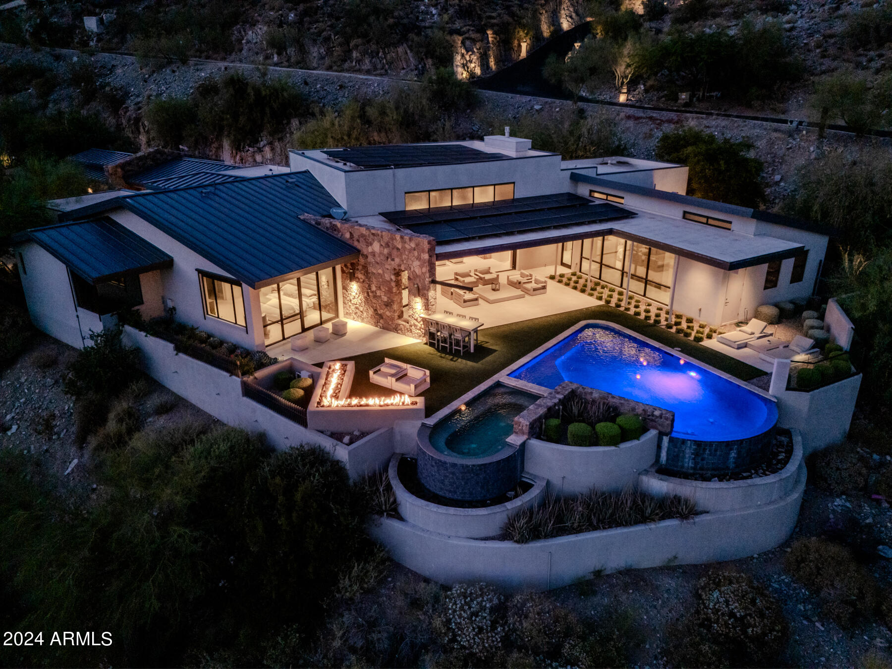 Rarely available single level hillside home in the most prestigious gated community in Paradise Valley.  This single-level modern contemporary masterpiece offers stunning views of Camelback Mountain day and night. Solid walnut doors with brushed aluminum inlays, custom cabinets, and Brazilian teak accents adorn the interior, complemented by a standing seam metal roof. The chef's kitchen features limestone/Spekva Wood countertops from Sweden & Thermador appliances. The kitchen seamlessly connects to the Great Room: Open the motorized doors to the resort-style pool area on one side, and the outdoor kitchen on the other for a true indoor/outdoor lifestyle and enjoy views of Camelback Mountain and the city lights of Phoenix.  The extra large master bath features Carrera Marble