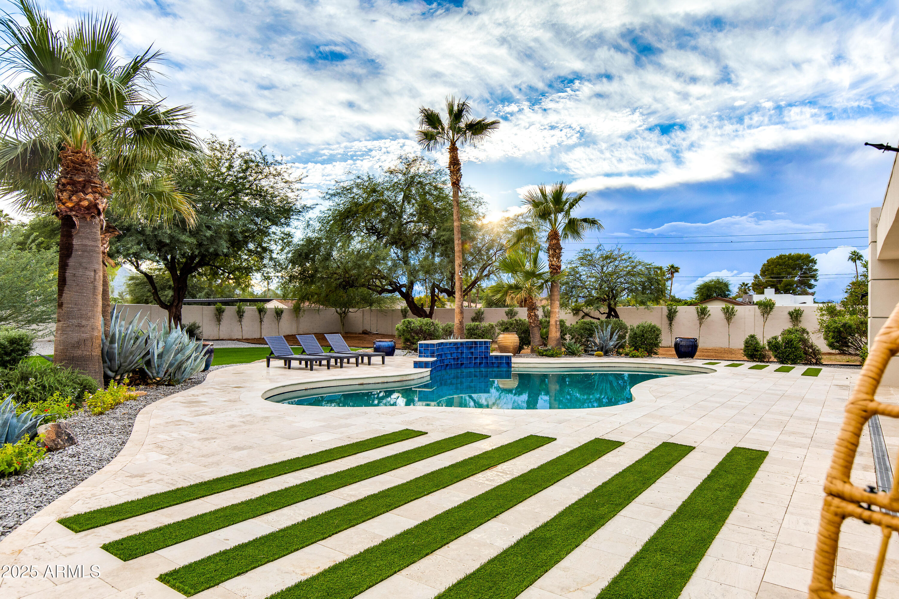 Masterfully reimagined modern estate on a 35,478 sq. ft. private lot in the heart of Paradise Valley. A circular paver driveway, modern steel-and-glass entry, and newly raised front and back entry ceilings lead into a bright, open interior with vaulted ceilings, exposed beams, oversized designer tile, and a dramatic floor-to-ceiling stone fireplace. Expansive glass doors create seamless indoor-outdoor living with views of the resort-style backyard. The property also features beautiful front and rear sitting areas ideal for relaxing or entertaining. The flexible layout offers 5 bedrooms and 4 bathrooms, including a dedicated bedroom wing with a junior suite and a split primary suite for privacy. The third wing includes a spacious laundry room and a contemporary office or fifth bedroom. The chef's kitchen showcases a massive waterfall island, custom cabinetry, Thermador appliances, induction cooktop, and a glass-front wine display. The spa-inspired primary suite includes a sculptural soaking tub, oversized dual-rain shower, and a boutique-style custom closet. Outside, enjoy a curved pool with raised water feature, travertine surround, a covered patio with floor-to-ceiling fireplace, BBQ area, and warm wood-notched ceiling. Multiple dining and lounging areas, mature trees, and layered desert landscaping complete the resort feel. Fully remodeled with a 500 sq. ft. addition and raised casita, or expand the garage to suit your vision. Ample parking and room for multiple vehicles enhance flexibility. Moments from world-class resorts, dining, golf, and hiking...modern luxury in one of Arizona's most desirable locations.