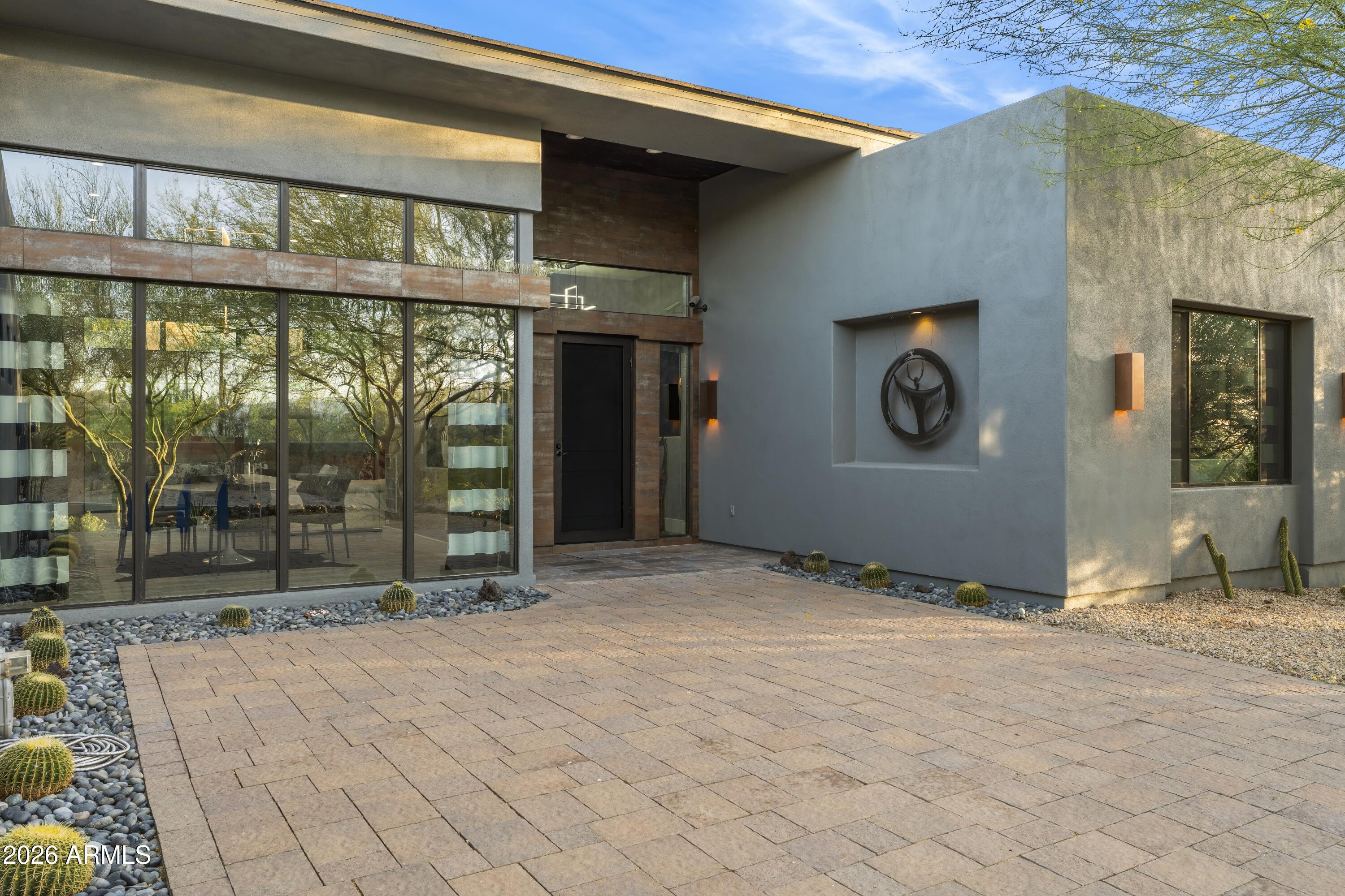 Modern, Minimal & Move-in Ready. Custom contemporary lock & leave luxury masterpiece designed by Tyler Green in gated Ridgeview Estates. This pristine, single-level home features an open floor plan with soaring 14' ceilings & no steps. The thoughtful split layout ensures privacy, separating the primary from 2 guest bedrooms, each with en-suite baths & walk-in closets. Enjoy multiple dining options with a breakfast room, kitchen island, formal dining & al fresco. The private, fully fenced backyard borders a serene desert wash, highlighted by low-maintenance landscaping & paver surfaces that span both front & back. The garage includes abundant built-in cabinets. Meticulously kept by the original owner, this home is walking distance to Carefree dining, galleries, shopping & entertainment