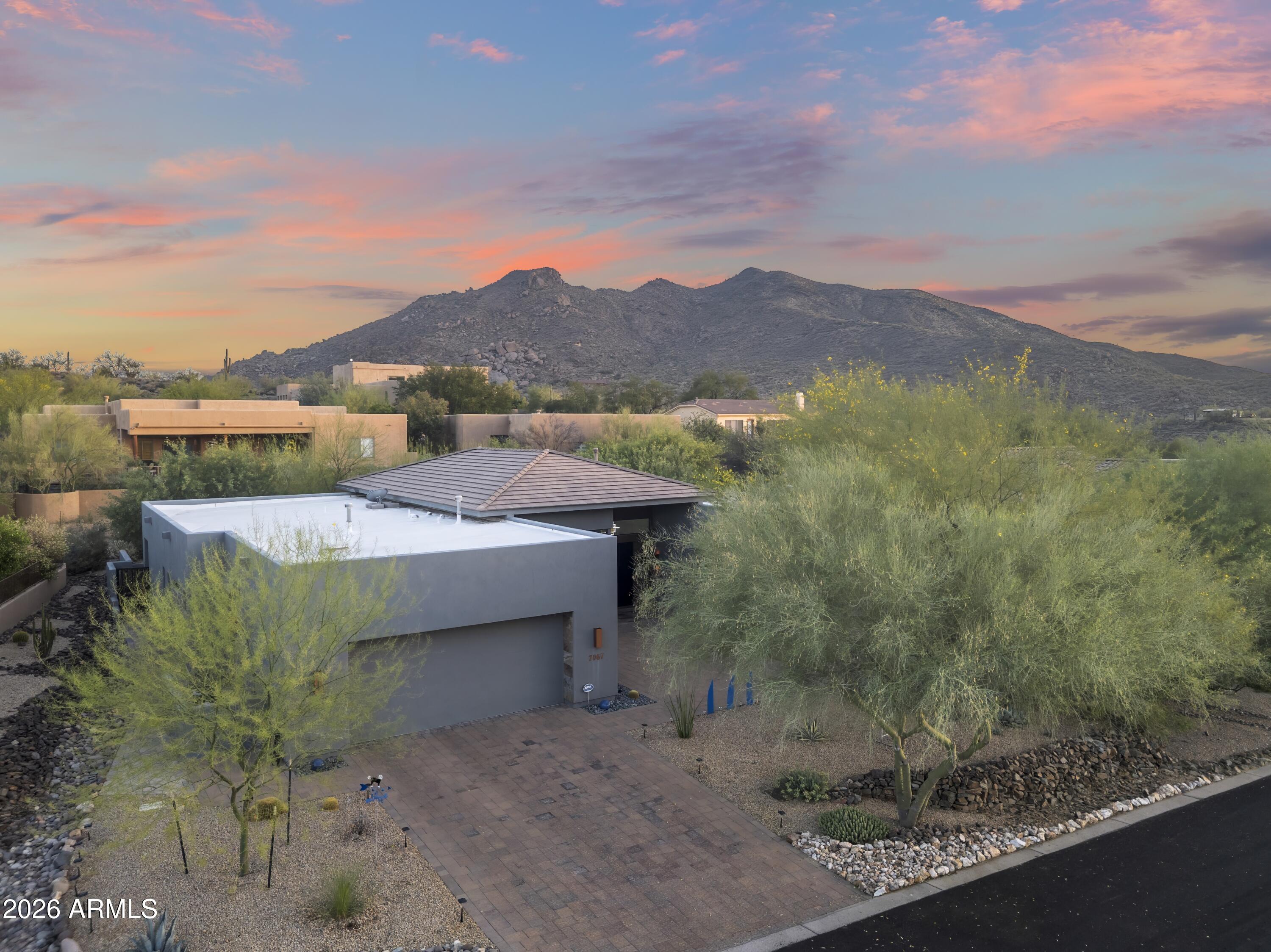 Modern, Minimal & Move-in Ready. Custom contemporary lock & leave luxury masterpiece designed by Tyler Green in gated Ridgeview Estates. This pristine, single-level home features an open floor plan with soaring 14' ceilings & no steps. The thoughtful split layout ensures privacy, separating the primary from 2 guest bedrooms, each with en-suite baths & walk-in closets. Enjoy multiple dining options with a breakfast room, kitchen island, formal dining & al fresco. The private, fully fenced backyard borders a serene desert wash, highlighted by low-maintenance landscaping & paver surfaces that span both front & back. The garage includes abundant built-in cabinets. Meticulously kept by the original owner, this home is walking distance to Carefree dining, galleries, shopping & entertainment
