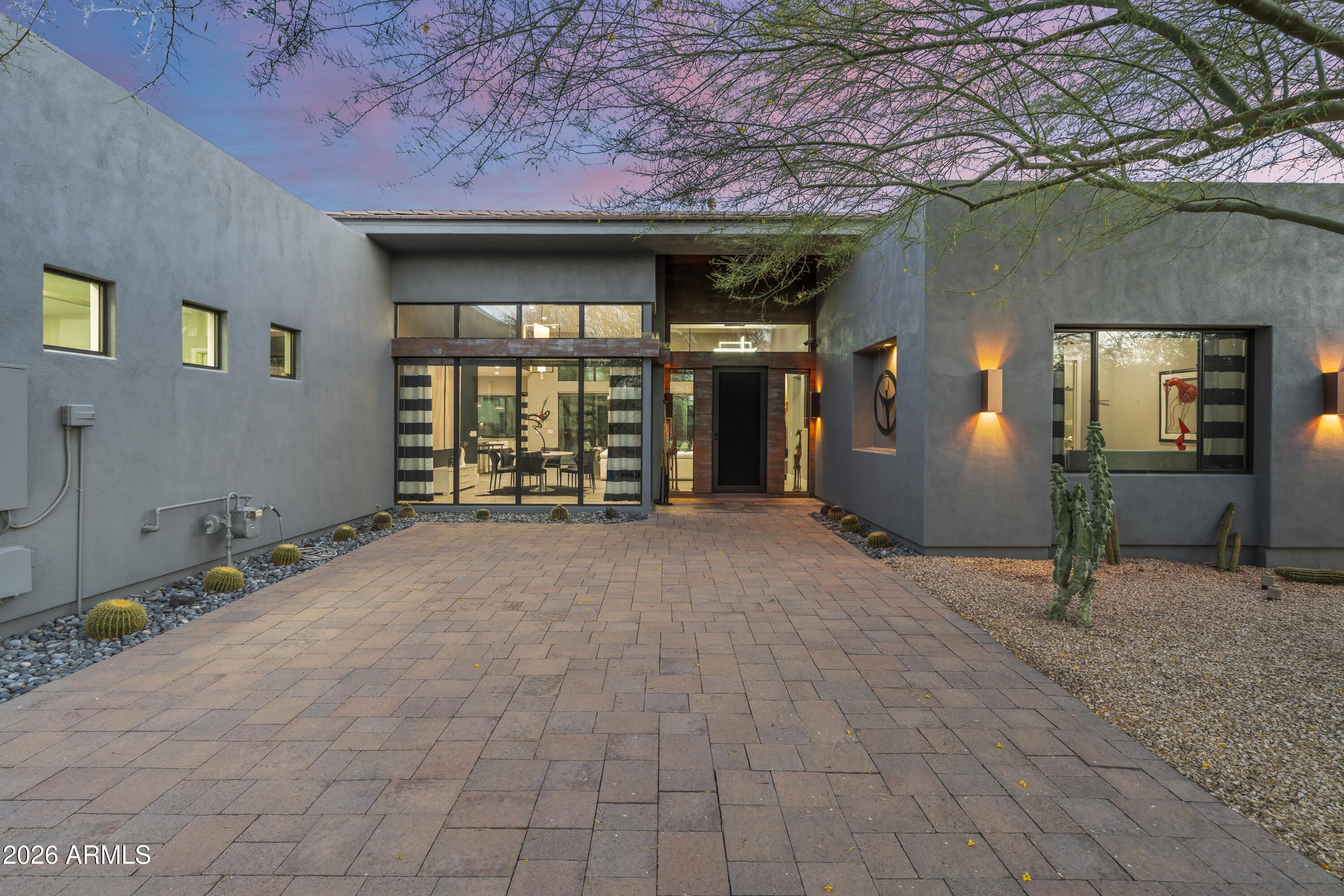Modern, Minimal & Move-in Ready. Custom contemporary lock & leave luxury masterpiece designed by Tyler Green in gated Ridgeview Estates. This pristine, single-level home features an open floor plan with soaring 14' ceilings & no steps. The thoughtful split layout ensures privacy, separating the primary from 2 guest bedrooms, each with en-suite baths & walk-in closets. Enjoy multiple dining options with a breakfast room, kitchen island, formal dining & al fresco. The private, fully fenced backyard borders a serene desert wash, highlighted by low-maintenance landscaping & paver surfaces that span both front & back. The garage includes abundant built-in cabinets. Meticulously kept by the original owner, this home is walking distance to Carefree dining, galleries, shopping & entertainment