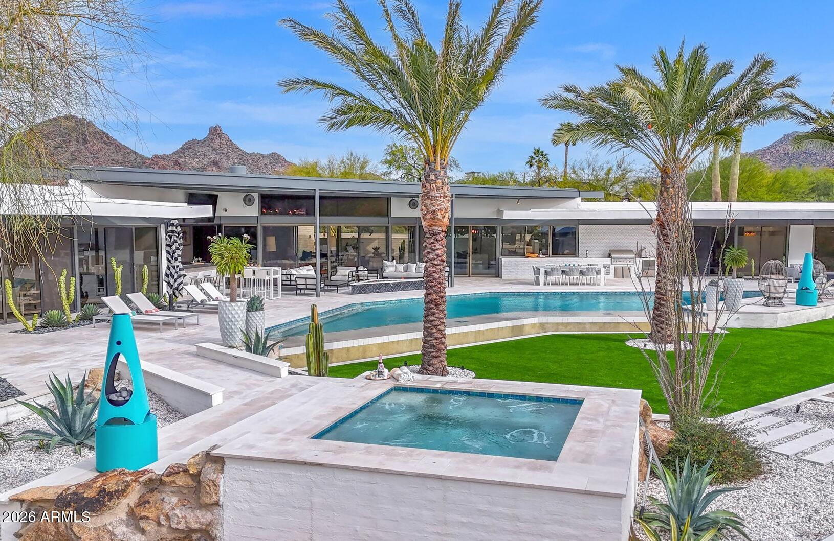 Authentic 1980 Al Beadle desert modern residence is set on 5 private gated acres in North Scottsdale and has been totally reimagined with over $1.3 million invested since 2022. Panoramic mountain, desert and sunset views are yours from every window and every angle, with architecture and landscape working in perfect harmony. The main residence encompasses dramatic open living with custom TV / fireplace wall hand crafted from walnut and steel at its center. The 300 bottle glass wine wall leads to redesigned gourmet kitchen with dual quartz islands, custom cabinetry and Wolf/Sub-Zero appliance suite. Fabulous remodeled vintage bar with floor to ceiling artisan tile, new ice maker & bar sink offers a fun place to gather with guests, with custom sliding windows to the outdoor entertaining area. These spaces all share the stunning views to the south thanks to Beadle's vision for room orientation in his original design. The split primary wing to the west with a private office is intimate yet sizable, with elegant walk in shower, two large closets and a second stacked laundry center. Three additional guest rooms, three luxuriously appointed private baths plus powder room, spacious laundry center / walk-in pantry round out the main house layout. The attached fully integrated 2-bedroom guest casita is accessed from the back patio and features private bath and kitchenette; this space is beautifully suited for guests, multigenerational living or staff. Brand new fitness center brings daily workouts to a new level, offering desert harmony with its sliding doors to a private patio on the north end of the garage spaces. Integrating today's modern technology is the Crestron smart home system which controls A/V, security, lighting, shades, front gate, landscape, outdoor TVs and audio. Signature Beadle lines, walls of glass, and seamless indoor/outdoor connections are preserved while all systems and finishes are elevated to modern luxury standards. Resort grounds have been completely reinvented to celebrate the original aesthetic but to also add an unmatched level of luxury: reconfigured pool and new spa, limestone hardscape, over 3000 square feet of turf, specimen palms and desert plantings, two fire features including a steel-beam fire pit gazebo, bocce ball and a fully updated outdoor kitchen with bar seating and 82" TV. Resurfaced tennis court with two pickleball courts, breeze-block accents and private gated entry complete this rare desert compound. For those who appreciate architecture, privacy, views and a fully realized modern desert lifestyle, this Beadle estate is one of a kind in North Scottsdale. Location could not be more convenient, just minutes from shopping, dining and signature Scottsdale events.