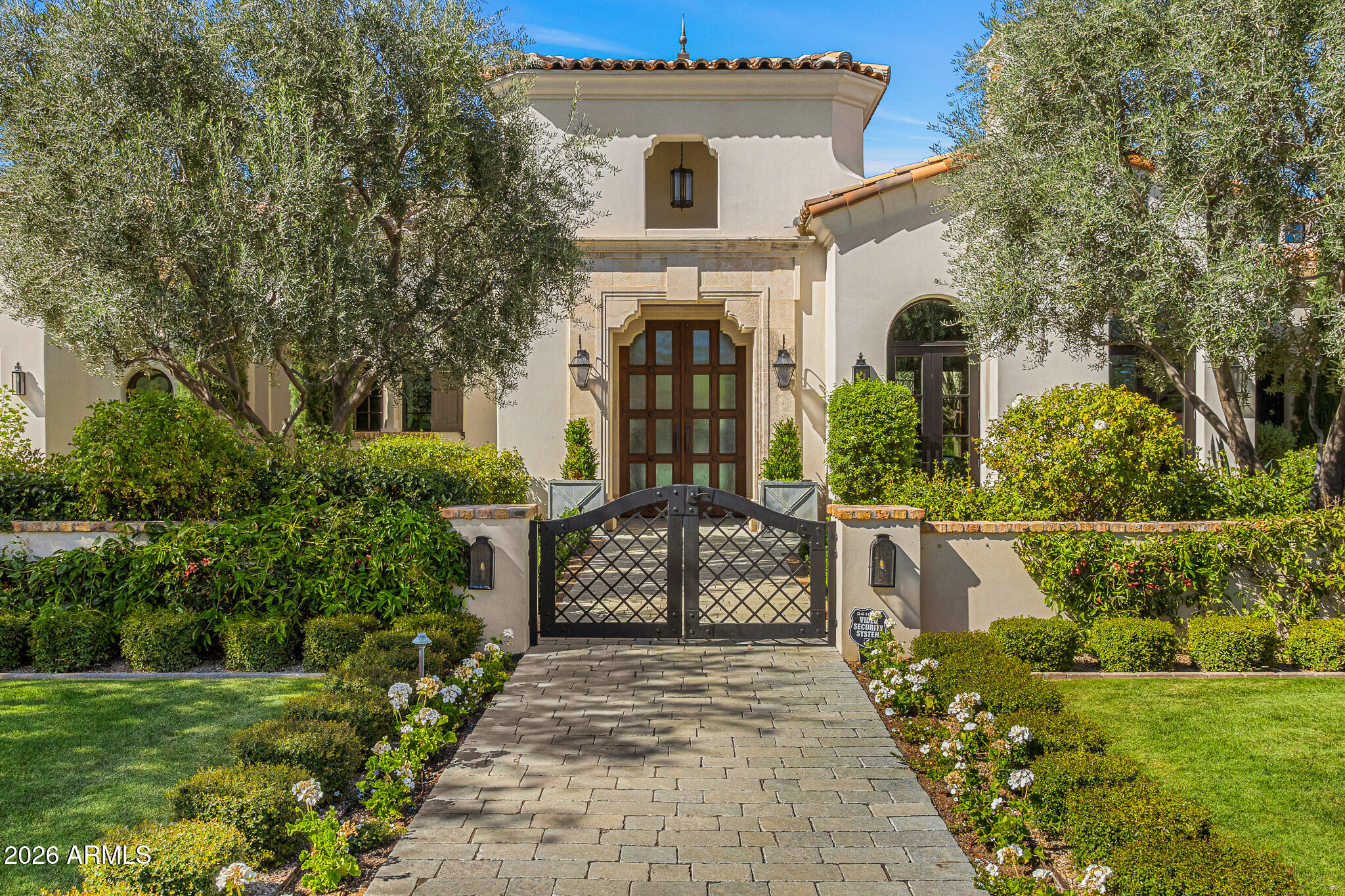 Privately gated and set on 1.1 acres of lush, mature landscaping, this timeless Santa Barbara estate offers unobstructed mountain views in the heart of Paradise Valley's coveted Equestrian Trails. Designed by renowned architect Matthew Thomas, built by Mike Foster Custom Homes, with landscape design by Berghoff Design Group and curated lighting by Walter Spitz, this 9,347 square foot residence is a true collaboration of craftsmanship and design excellence.
A grand entry reveals perfectly framed views of the saltwater pool and manicured grounds, setting the tone for the home's effortless elegance. Soaring ceilings, handcrafted architectural details, and expansive living spaces create a refined yet inviting atmosphere. The thoughtfully designed floor plan includes five spacious ensuite .... bedrooms and seven and a half beautifully appointed bathrooms.
At the heart of the home, the kitchen overlooks a serene courtyard and features custom Desert Cove cabinetry, matte Carrera marble countertops, top tier appliances, and a striking solid walnut island beneath a light filled cupola with a statement chandelier. The space flows seamlessly into the great room, where accordion doors open to covered patios, private gardens, and beautifully curated outdoor living spaces that capture the essence of indoor outdoor living.
The west wing is anchored by a luxurious primary retreat with a spa inspired bath, dedicated fitness room, and two private courtyards. The east wing offers three additional ensuite bedrooms, a playroom with tongue and groove ceilings and cupola detail, and a state of the art theater with custom leather doors.
A true showpiece, the attached guest house designed as a refined party barn features reclaimed 100 year old Idaho wood, blending history with elevated design. Complete with a full kitchen, wine fridge, loft bedroom with full bath, additional powder baths, laundry, and its own air conditioned garage, this space is ideal for large scale entertaining while maintaining privacy from the main residence. Accordion doors open to a heated patio with firepit and café lighting, creating a warm and inviting setting for gatherings.
The grounds are equally impressive, showcasing a lush vegetable garden, mature trees, and a newly added putting green, all thoughtfully integrated into the estate's beautifully landscaped setting. The resort style grounds are anchored by a sparkling saltwater pool and designed for both relaxation and entertaining.
Located in one of Paradise Valley's most prestigious enclaves, this architectural masterpiece offers a rare combination of privacy, tranquility, and proximity to world class dining, shopping, and recreation. A true legacy estate crafted with intention, designed to inspire, and built to stand the test of time.
