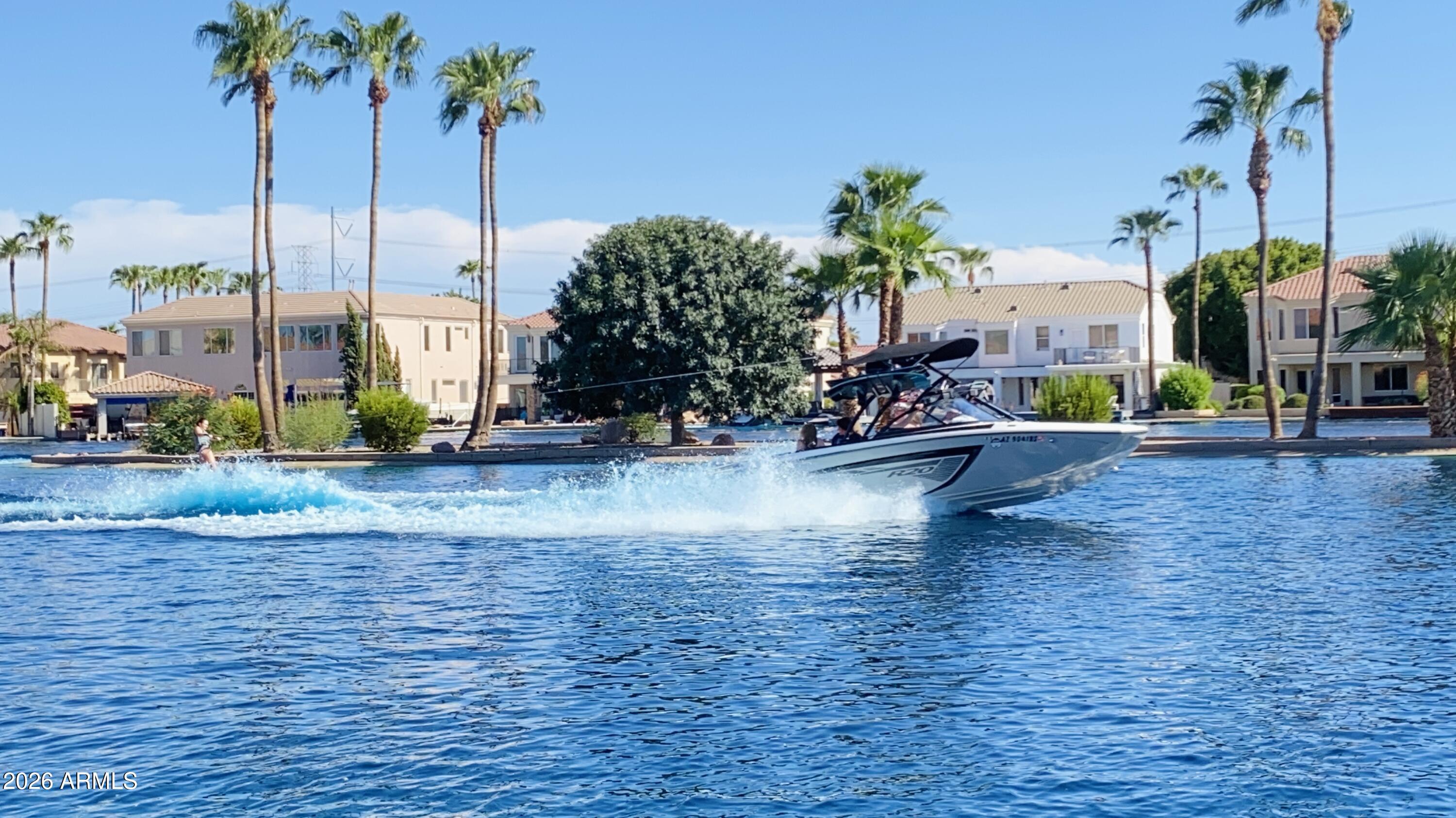 One-time price adjustment. All offers will be reviewed. Existing furniture throughout the home is available and may be included for buyers who wish to keep it. There are only six waterski lakes in the entire Phoenix metro area; three in Gilbert, one in San Tan Valley, and two in Buckeye. Across the East Valley (Gilbert & San Tan Valley), there is currently only one home available for sale, and it is this waterfront property in Playa del Rey Estates. At Playa del Rey, residents enjoy true lakefront living with an exceptional range of recreational activities, including water skiing, jet skiing, boating, kayaking, paddleboarding, towable inflatables, and speeds up to 36 mph. In addition, the community features a second lake dedicated to catch-and-release fishing, offering a rare combination of active recreation and peaceful retreat. What truly sets Playa del Rey apart is its unmatched versatility-unlike most ski lakes designed primarily for tournament use, or other lake communities that restrict water access altogether, this is the only community in the area that fully embraces a broad, year-round waterfront lifestyle.

Beyond the lakes, Playa del Rey is a gated 24/7 community with outstanding amenities, including a brand-new mini golf course with fountain features, clubhouse, basketball court, and floating dock. Residents also enjoy a full calendar of community events throughout the year, including Easter celebrations, trick-or-treating, holiday festivities, and more.

The home itself is completely turnkey and was extensively remodeled between 2019 and 2020. Highlights include a gourmet kitchen designed for entertaining, spa-inspired renovated bathrooms, and a luxury Savaria elevator providing effortless multi-level access. Automated stackable Pella sliding doors create seamless indoor-outdoor living while filling the home with natural light.

The layout is both functional and thoughtfully designed, featuring two en-suite bedrooms one on each level plus three additional bedrooms, a dedicated den, game and family rooms, formal living and dining spaces, and a convenient laundry chute. High ceilings, generous bedroom sizes, wide hallways, and an open flow throughout the home create a perfect balance of comfort, privacy, and effortless entertaining. Welcome home!