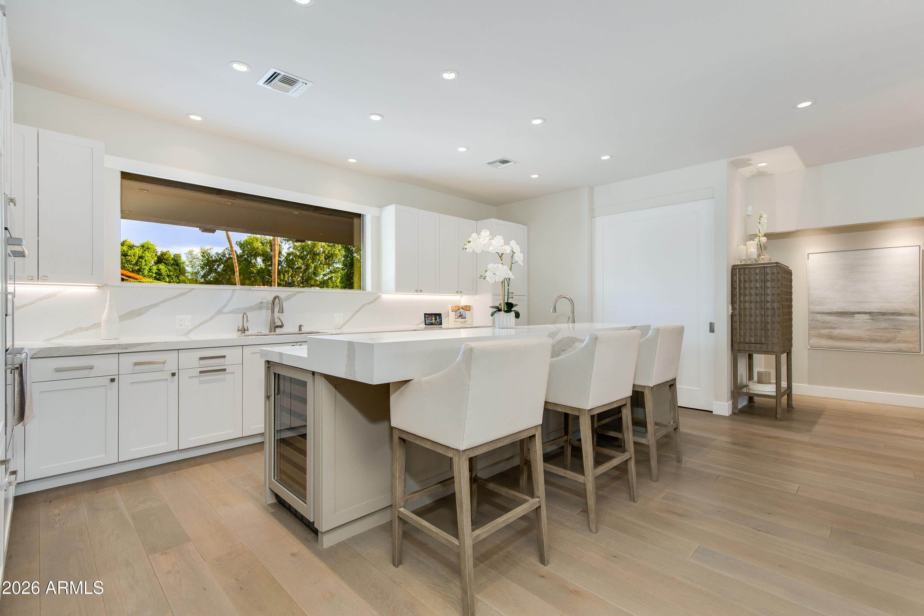 A rare residence in the guard-gated Biltmore Greens community! This thoughtfully reimagined home showcases unmatched design, refined finishes, and seamless indoor/outdoor living. The open-concept split floor plan with no interior steps is anchored by vaulted ceilings with exposed beams, expansive walls of glass, and a statement fireplace that creates a warm yet sophisticated living space. The spacious primary suite offers dual closets, tranquil backyard views, and direct pool access, while two additional guest bedrooms are privately situated with en-suite baths, plus a stylish powder bath for guests. Outside, the private resort-style backyard was redesigned with a heated pool, spa, outdoor kitchen, stone patio with turf accents, and multiple areas to relax or entertain. Ideally suited as either a full-time residence or lock-and-leave retreat, this exceptional home offers effortless access to the iconic Arizona Biltmore, premier golf courses, upscale dining, luxury shopping, and Sky Harbor Airport.