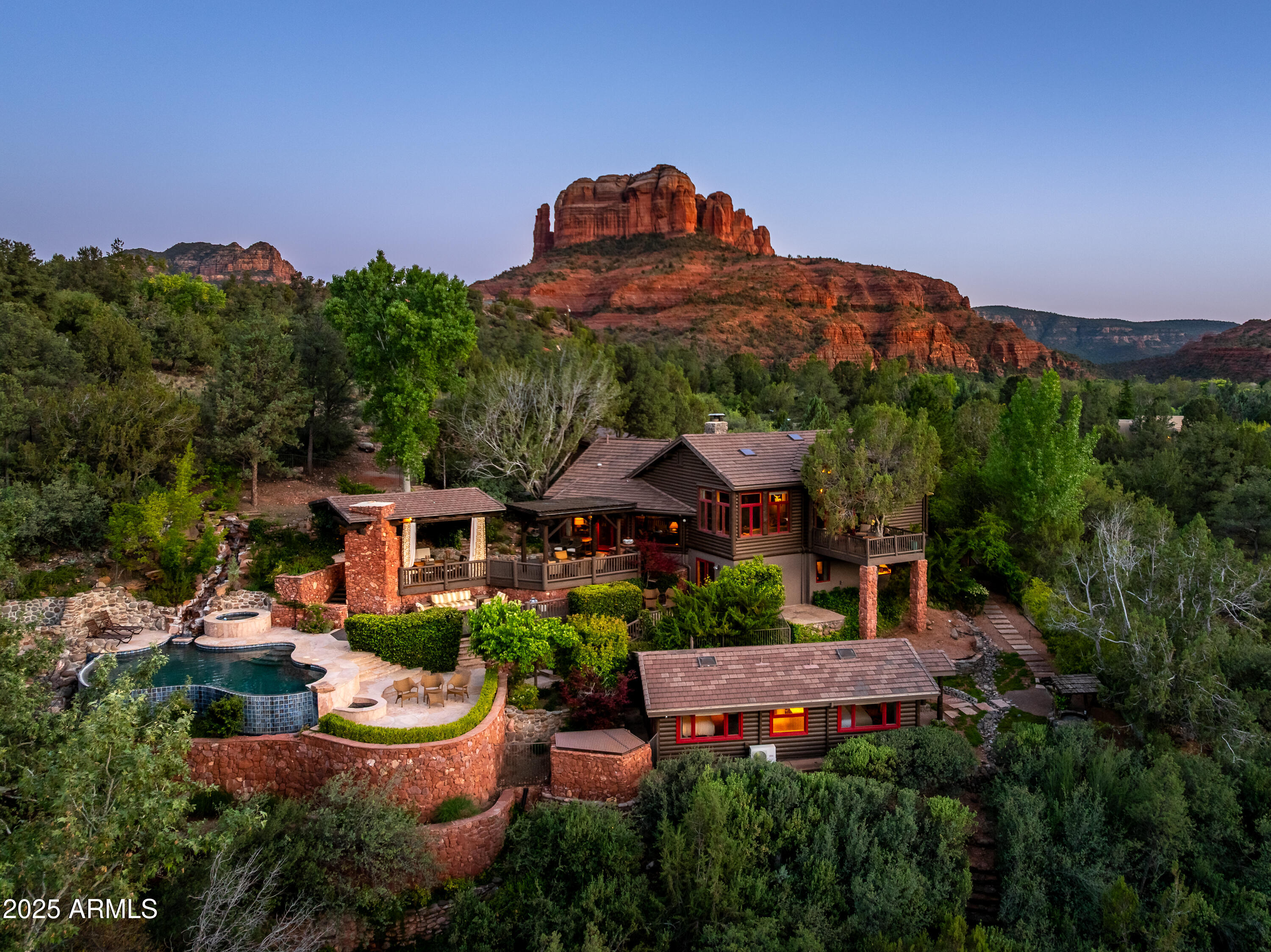 Sedona creekside luxury home with amazing cantilevered pool and spa overlooking the winding waters of Oak Creek. Located in one of Sedona's most exclusive neighborhoods, this legacy property has been owned and beloved by AZ pedigree - including AZ Governor/US Secretary Babbitt. This elevated log cabin and detached 2 bedrooms guest home is an elite waterfront escape with red rock views and has been highlighted in more design magazines and TV shows than any other in Sedona. This is a cabin like no other in Sedona - if Ralph Lauren wanted a southwest escape he'd have crafted this high quality exposed beam, wood flooring, log masterpiece - an elevated remodel without a budget. Newly remodeled backyard with negative edge pool and spa with private trail access to the shores of Oak Creek. Main house has 2 bedrooms on 2 levels, lower level primary suite, 2.5 baths, 3 fireplaces, comprising a total of 3,067sf with framed views of Cathedral Rock and 176' of creek frontage. Luxury "Old Sedona" home features Arizona pine timbers with rugged exposed trusses and beams with soaring ceilings of knotty pine T+G. Original Arizona Schist stone fireplace and surrounding reading space. Hand planed walnut flooring, custom gallery lighting; and vintage chandeliers. Massive kitchen with river rock accents opens onto an outdoor patio with direct Cathedral Rock views for ideal sunset cocktail hour. Lower level of the home is a massive primary suite complete with river rock fireplace, amazing en suite setup with separate tub and shower, walk in closets and its own washer and dryer.
Detached casita is just steps away from the main house and loggia showcasing a single level 2 bedroom cabin with shared .75 bath - offering luxury and privacy for your guests.

Separate Art Studio/Office/home gym abutting the 2 car garage: Heated/cooled space totaling 258sf - ideal for home gym or bike storage, yoga studio, podcast studio or home office professionals.