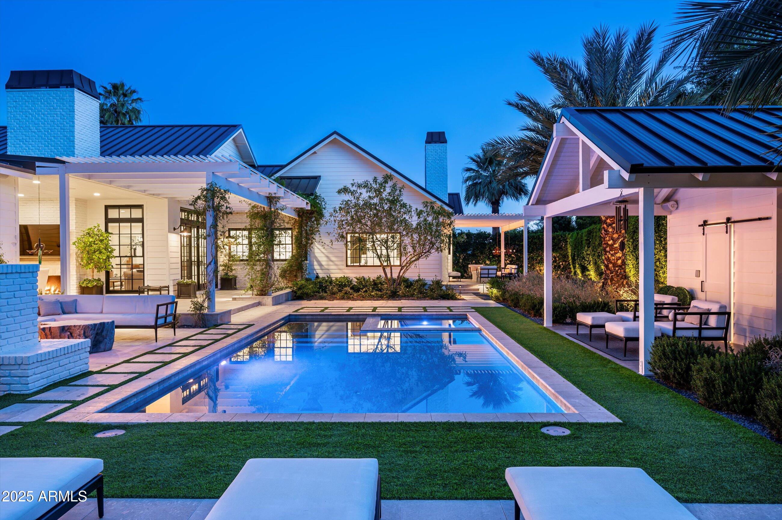 Discover an unrivaled sanctuary where classic Southern charm meets the pinnacle of modern luxury. Nestled in the heart of Arcadia on coveted 49th Place—where over 80% of homes are stunning new builds—this extraordinary estate is a true testament to timeless design and uncompromising quality, a masterful 2018 collaboration by the renowned trio of Two Hawks Design & Development, Design Lab Architects, and Jaimee Rose Interiors. This is not merely a home; it is a legacy.

Step inside and feel the home come alive. Natural light spills through floor-to-ceiling windows, illuminating a canvas of crisp whites, rich wide-plank floors, and authentic hand-hewn beams. Every detail has been meticulously considered, from the inviting glow of five fireplaces to the state-of-the-art Control4 AV system and automatic window treatments that effortlessly shape your environment.

Beyond the main living spaces, a breathtaking master retreat offers a private escape, while the dedicated executive-ready office provides a command center for your professional world. Spanning just over 6,000 square feet, the generous floor plan balances efficiency and elegance, offering a seamless flow for grand-scale entertaining or quiet, intimate moments.

Step outside to the resort-style west-facing backyardwidely regarded as the finest west-facing lot in all of Arcadia. Lush, mature landscaping and strategic north-facing orientation create cooling shade and serene privacy, delivering the feel and comfort of a true north-facing oasis even through golden Arizona afternoons. With more than 1,500 square feet of covered outdoor entertaining space, this is seamless indoor-outdoor living perfected. Enjoy the gracious front porch, where flickering gas lanterns welcome you and frame majestic, unobstructed views of Camelback Mountain. 

This exclusive listing is a rare opportunity, reserved for those who seek the extraordinary. With a whole-home Cummins generator providing ultimate peace of mind, this home is equipped for an unparalleled life of comfort and convenience.

This is a property that transcends the ordinary and sets a new standard for luxury living. It is a feeling, an experience, and a promise of a life well-lived.