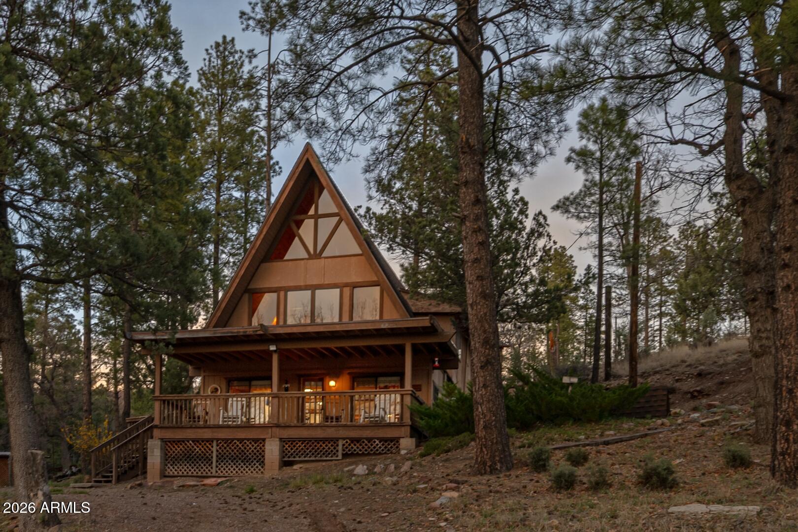Welcome to your peaceful retreat in Ponderosa Springs! This charming three-level cabin nestled in the woods offers three bedrooms and two bathrooms, perfectly blending rustic warmth with comfortable living. The main level boasts soaring vaulted ceilings, abundant natural light from large windows, and beautiful tongue-and-groove knotty pine throughout. Highlights include a cozy pellet stove, an open-concept family/living room flowing into the kitchen with eat-in dining and breakfast bar, a spacious primary bedroom, a full bathroom and a convenient walk-in pantry. A large storage room with cabinetry provides ample space for organization. A custom wooden spiral staircase leads to the second level, featuring large windows, a propane gas heating stove, a fun bunk room for the kids/teens, a second family/living area, a full bathroom, and a laundry/mud room. Another spiral staircase ascends to the private loft bedroom with privacy drapes. Every level offers stunning forest views. Outside, enjoy a covered front porch, one acre + of serene, private wooded land, and two large sheds for extra storage - located near the Rim Lakes in Unit 23 where temperatures are always 30 degrees cooler than the Valley. Privately sourced well water enhances the property's self-sufficient, cabin lifestyle. Whether you're looking for a cozy Arizona A-frame cabin for the whole family or a serene getaway to create lifelong memories, this is the one!