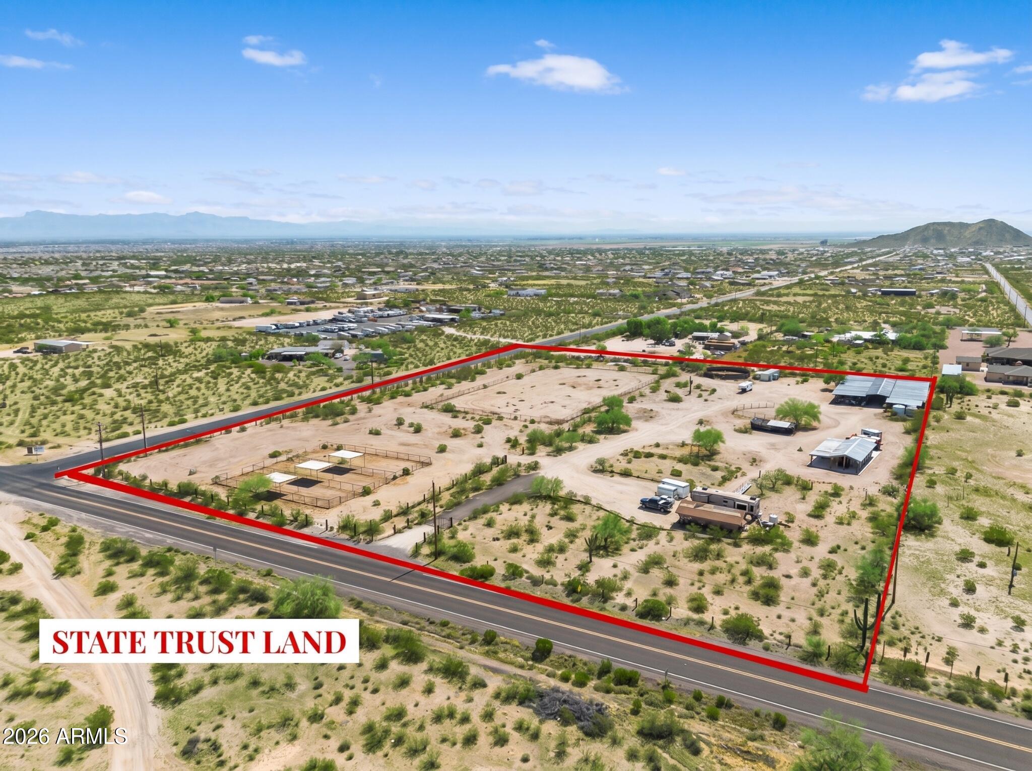 Rare 7-acre horse property directly across from State Trust Land & San Tan Mountain Regional Park, offering incredible trail access for horseback riding, hiking, & biking. On well water & EPCOR service is available at the property line. 2 parcels sold together as 1 property, creating a premier equestrian estate, custom home site, or legacy ranch opportunity. Equestrian improvements include 16 covered horse stalls, turnouts w/ 3-6 stalls, a round bullpen & roping length arena. RV Hookups, no HOA! Ride straight from the property onto miles of trails. Panoramic San Tan Mountain views, breathtaking Arizona sunsets, star-filled skies, & distant city lights. Ranch home could be used as primary residence or guest quarters. Rare acreage in a growing corridor, just minutes to city amenities. This property comes ready for the full homestead lifestyle -- a chicken coop for your flock and a dedicated tack/tool shed to keep gear organized and out of the weather.    Close to Horseshoe Park & Equestrian Centre, shopping, dining, schools, and everyday conveniences while still offering the space, views, and privacy of acreage living.  
One parcel includes an existing 1974 dwelling, offering the potential to reduce future impact fees for a new custom home (buyer to verify). Combined APNs 509-15-046 and 509-15-047. Suburban Ranch (SR) zoning on both parcels.