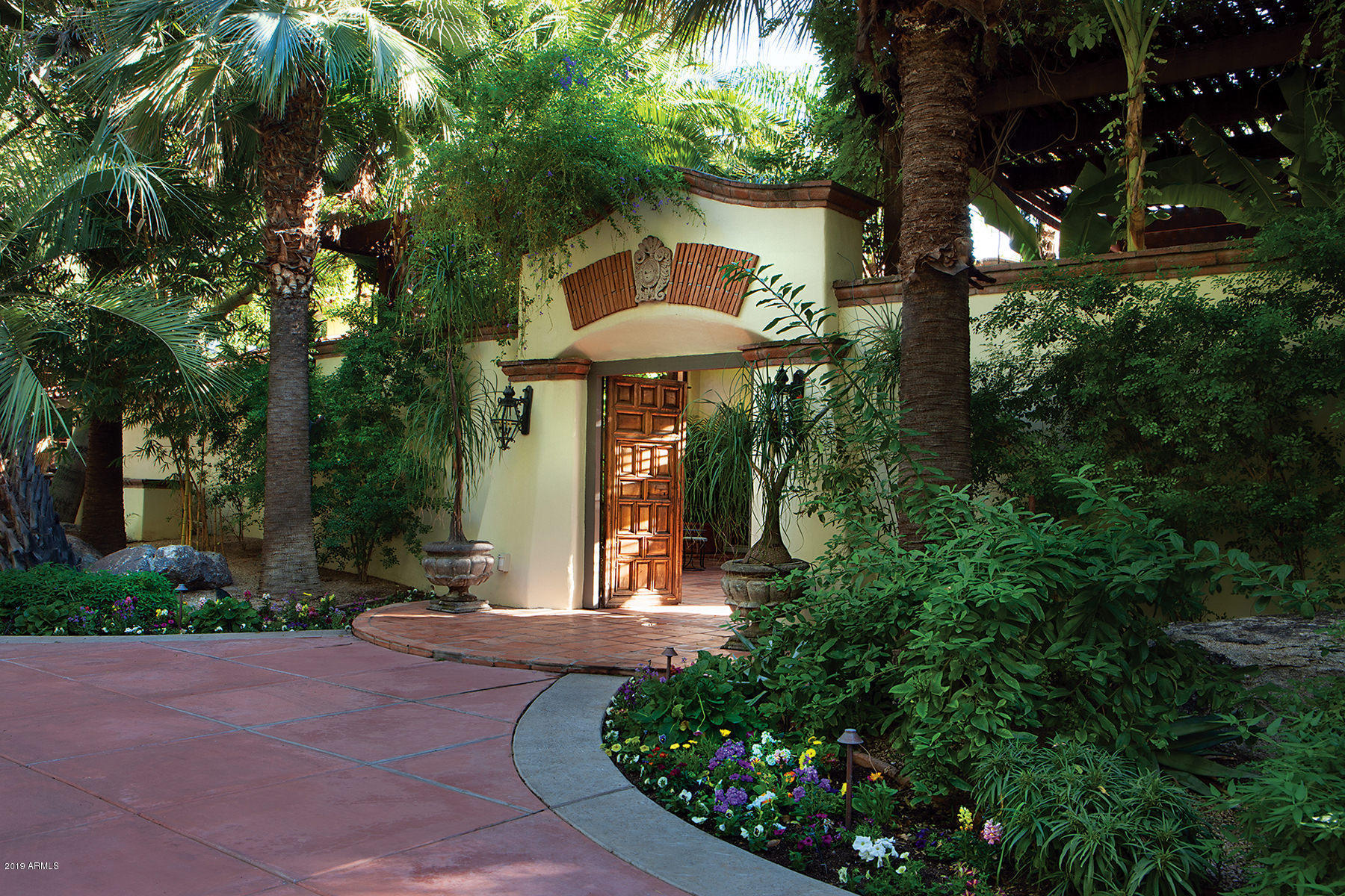 Price Reduction - now priced below recent appraisal. A beautiful example of timeless Spanish Colonial architecture designed by the renowned Lash McDaniel.  This one of a kind in Arizona, gated, turn-key and ready-to-move into two-acre compound is part of the coveted, quiet and private neighborhood of Bartlett Estates in the heart of the Biltmore area. It is a botanical paradise with fruit orchards, a wooded and shaded park-like lawn, a palm lined driveway, exotic landscaping, fountains, courtyards and balconies. The home incorporates only the highest end finishes including natural red oak floors, plaster walls, Spanish cedar cabinetry, custom carved fireplaces and rich moldings and trim throughout. The main house features a master retreat with a fireplace, French doors leading directly to a covered patio to the pool/spa, a his/hers bathroom with marble countertops, his/hers large closets, and a den with a wet bar and refrigerator off the master bedroom usable as a gym/nursery/entertainment room. There are three additional en-suite bedrooms and two other lovely half baths. The kitchen features all of the finest in cabinetry and appliances and a beautiful butlers pantry off the kitchen including a wet bar with ice maker, wine coolers and additional dishwasher. The adjacent breakfast room flows into the family room creating an open concept. A formal dining room and elegant living room each open to an amazing courtyard for entertaining and an in-home office with a fireplace, built-in custom cabinetry and wet bar opens to its own courtyard. You will want to live outside all year long under the covered patio near a wood burning fireplace when it's cool and under all of the mature shade trees when its's hot. Cook outside the main house kitchen at the oversized Lynx BBQ or at the Viking grill at the ramada that is next to the heated pool/spa and lovely canterra deck. The ramada has its own full bath, sink, Perlick ice maker, refrigerator and BBQ. Go shopping for organic vegetables and flowers at your own raised beds and greenhouse and for the fruits at your own flood-irrigated orchards - some of the fruits aren't even available in the store! Attached to the main house is a 530 sq ft guest casita with kitchenette, separate access and separate HVAC system. Steps away from the garden is another totally self-contained guest house newly renovated in 2018 with additional bedroom. Air conditioned two car garage, 4 covered carport spaces and ample additional parking. Tons of storage space. The main house square footage is 6,980 and the roomy detached guest house is 1,017 square feet. This is not just a house - this in an experience.