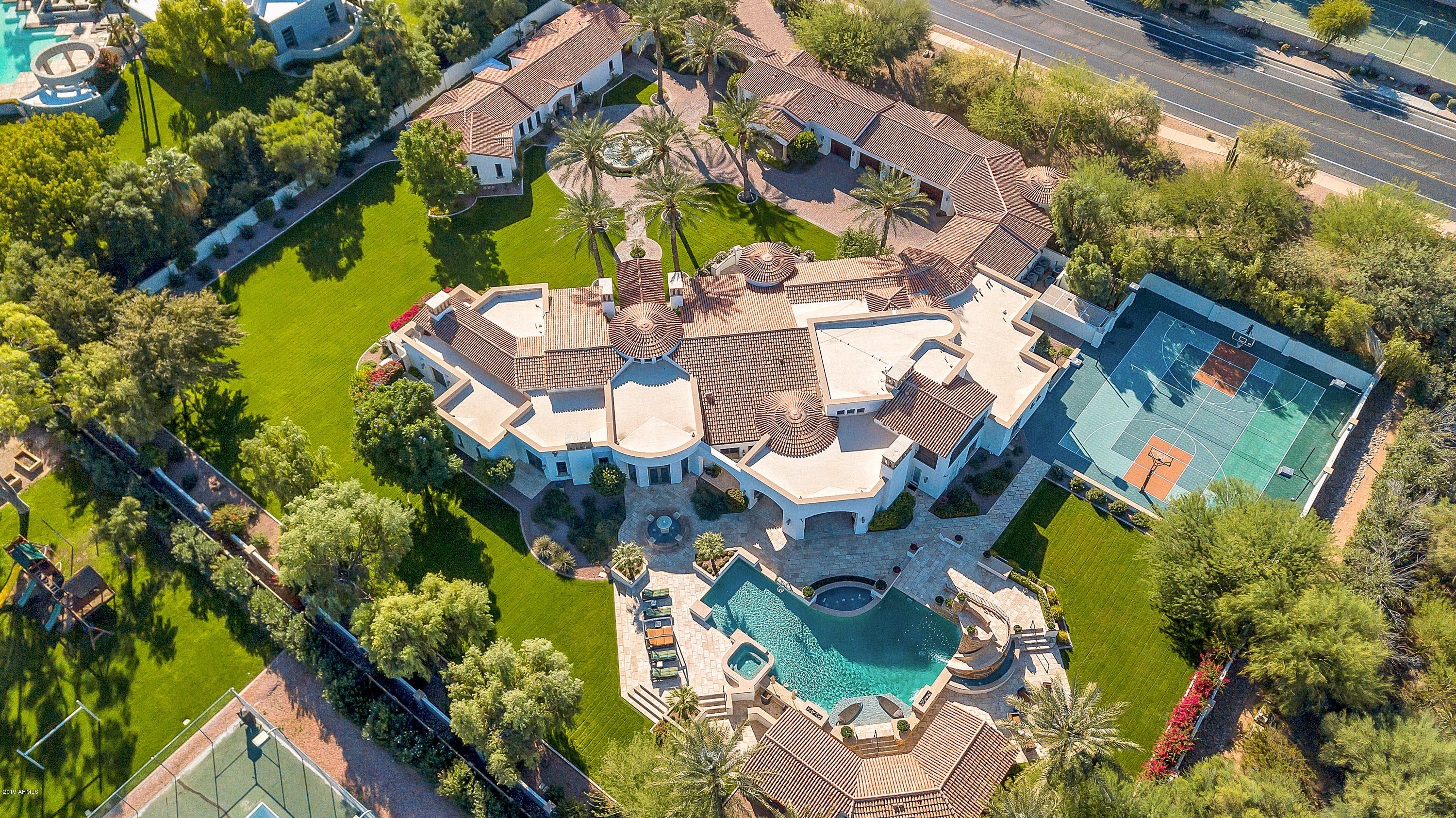 Gorgeous 2.24 acres luxury estate across from Camelback Mountain with multiple views of this Phoenix icon. Main home is nearly 10,000 square feet. Exquisite attention to detail begins with the iron doors to the foyer. Parlor with wet bar and views is perfect for guests. Chef's kitchen has two sinks, built in Subzero refrigerator and freezer, Wolf drop in gas range, double ovens and walk in pantry. Office with beautiful woodwork and wood ceilings has Camelback Mountain views. For big screen enthusiasts there is a home theatre and adjoining arcade. The master suite includes 2 fire places (in bedroom and bathroom), spacious walk in closet, gym, laundry room, private toilets, and a private retreat with water feature. The 3 additional main house bedrooms include en suites and walk in closets Backyard is an entertainer's dream with expansive yard space, 15 feet depth diving pool with water slide, covered patios with reverse osmosis misting system, water and fire features, a sport court with NBA regulation hoops, and a hidden outdoor shower with a private water fall. Car and shop enthusiasts will appreciate the 5-car garage with built in work stations/cabinetry. Guest Quarters are an additional 3,408 square feet including a 2bed/2.5 bath guesthouse and a 1bed/1.5bath casita. The Quarters each have their own private 1-car garages.