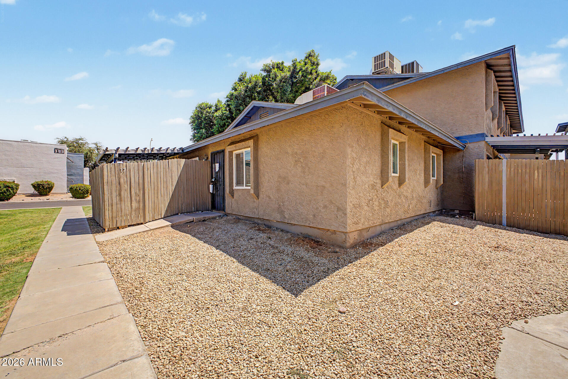 2-bedroom, 1-bath park-facing condo featuring tile and laminate flooring, ceiling fans throughout, built-ins in bedroom 2, and open living/kitchen area with recessed lighting and views of the community park. Sliding doors open to enclosed partially covered patio. Inside laundry, assigned covered parking space A17. Community includes palm trees throughout the community, pool, spa, and gazebo.