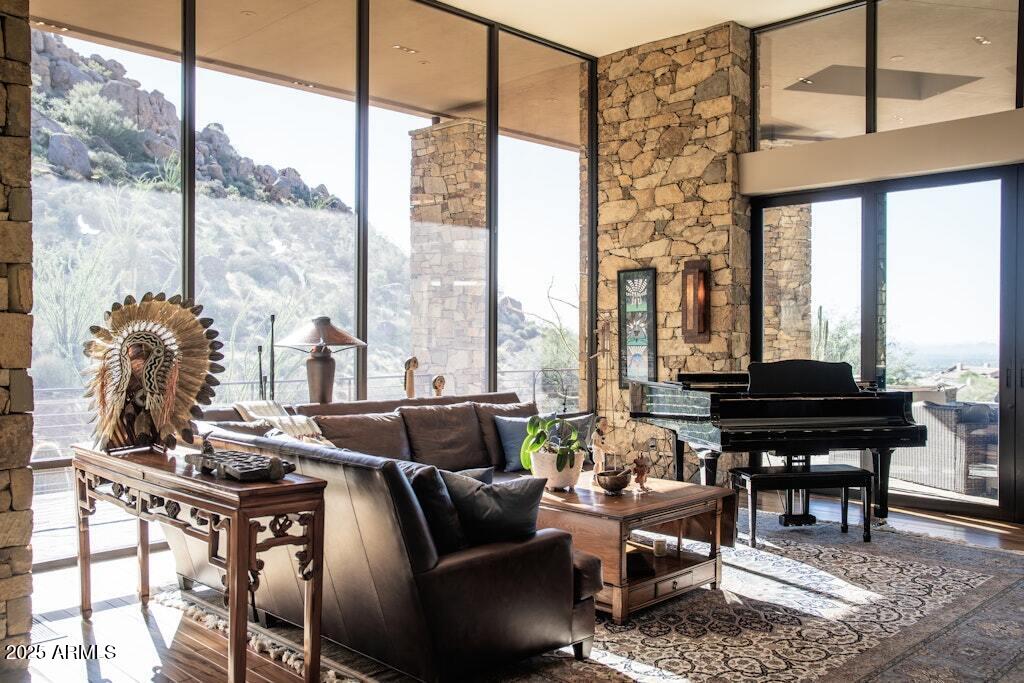 Situated on Troon Mountain, this private 5-acre estate offers expansive canyon views and sparkling city lights with no HOA dues or required memberships. Designed to blend naturally with its surroundings, the 7,247 sq. ft. residence features warm wood tones, stone accents, and a relaxed yet refined style reminiscent of a Ralph Lauren mountainside retreat. The home includes both indoor and outdoor living rooms, two full chef's kitchens, a media room, a 2,000-bottle wine room, and two detached guest suites that provide exceptional privacy for visiting friends and family. The main kitchen is equipped for true culinary needs, featuring BlueStar triple ovens (two electric and one gas), a Viking 7-burner gas range, dual dishwashers, double Sub-Zero refrigerators, an icemaker, and a trash compactor. The outdoor kitchen, set beneath a pergola, includes a Viking grill, Teppanyaki griddle, deep fryer, side grill, and refrigerator, making outdoor cooking and entertaining seamless.
The private primary suite offers a spa-like steam shower and a mountainside patio with a heated jacuzzi and fire bowl. Outdoors, multiple fire features, peaceful water features, and a glowing saltwater pool create a magazine-worthy setting, especially at sunset. Finishes throughout include natural stone details and rich woods such as tiger wood, ribbon mahogany, and Bubinga. A thoughtfully engineered roofline provides shade during the summer months while allowing winter sun to warm the stone floors. This "Park City" feel residence offers a rare combination of privacy, views, and timeless stylea true mountain side retreat located in the heart of North Scottsdale.