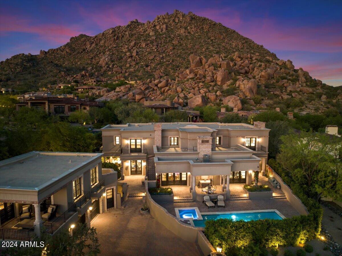 This remarkable custom estate is surrounded by boulders that make up what is the famous Troon Mountain. No expense spared remodel puts this homes all in spend at $4.5 Million dollars, making this offering even more attractive than the surrounding views. Inside this European inspired gem you will find immaculate living spaces throughout.  Boasting a flawless great room, a refined dining area poised to enhance your dining and entertaining occasions, a charming floor-to-ceiling brick fireplace that anchors both the breakfast room and kitchen, a graceful home office, and a primary suite seamlessly blending tranquility with comfort. Wood flooring, bespoke cantera stone, wooden beams, marble embellishments, and distinctive interior wood shutters imbue the exquisite design with character, while the open floor plan effortlessly harmonizes style and practicality. The guest quarters ensure ample privacy and offer splendid views. Surrounding the home are lush grounds, a stunning pool and spa with cascading waterfalls, and enchanting covered and uncovered patios that collectively create an unparalleled ambiance. This opulent residence truly epitomizes paradise! Totaling 8,448 square feet (including main and guest house).