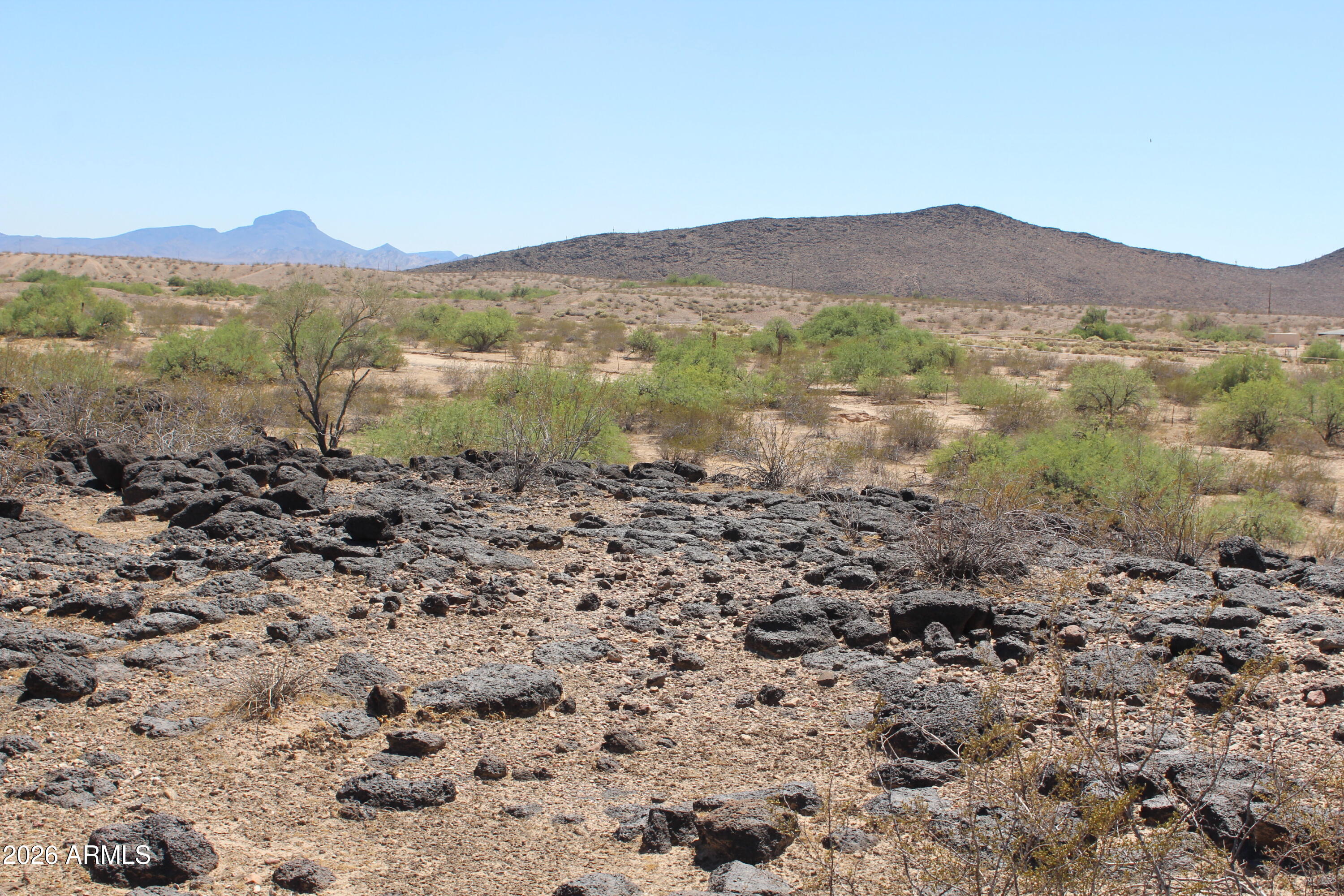 Discover 4.68 acres of opportunity in historic Arlington Farms, Rural Phoenix's hidden gem west of Buckeye. This secluded end-of-road parcel offers breathtaking mountain and desert views, unique volcanic rock features, and exceptional privacy rarely found today. Ideal for a custom home builder, homesteader, horse enthusiast, prepper retreat, or investor seeking a hard-to-find large acreage parcel. The property's natural elevation changes and wide-open space create a distinctive setting with endless possibilities. Convenient access to Buckeye and I-10 combines rural freedom with accessibility. Build your vision today or hold for tomorrow--large private parcels like this are becoming increasingly scarce in Arizona's growing West Valley.