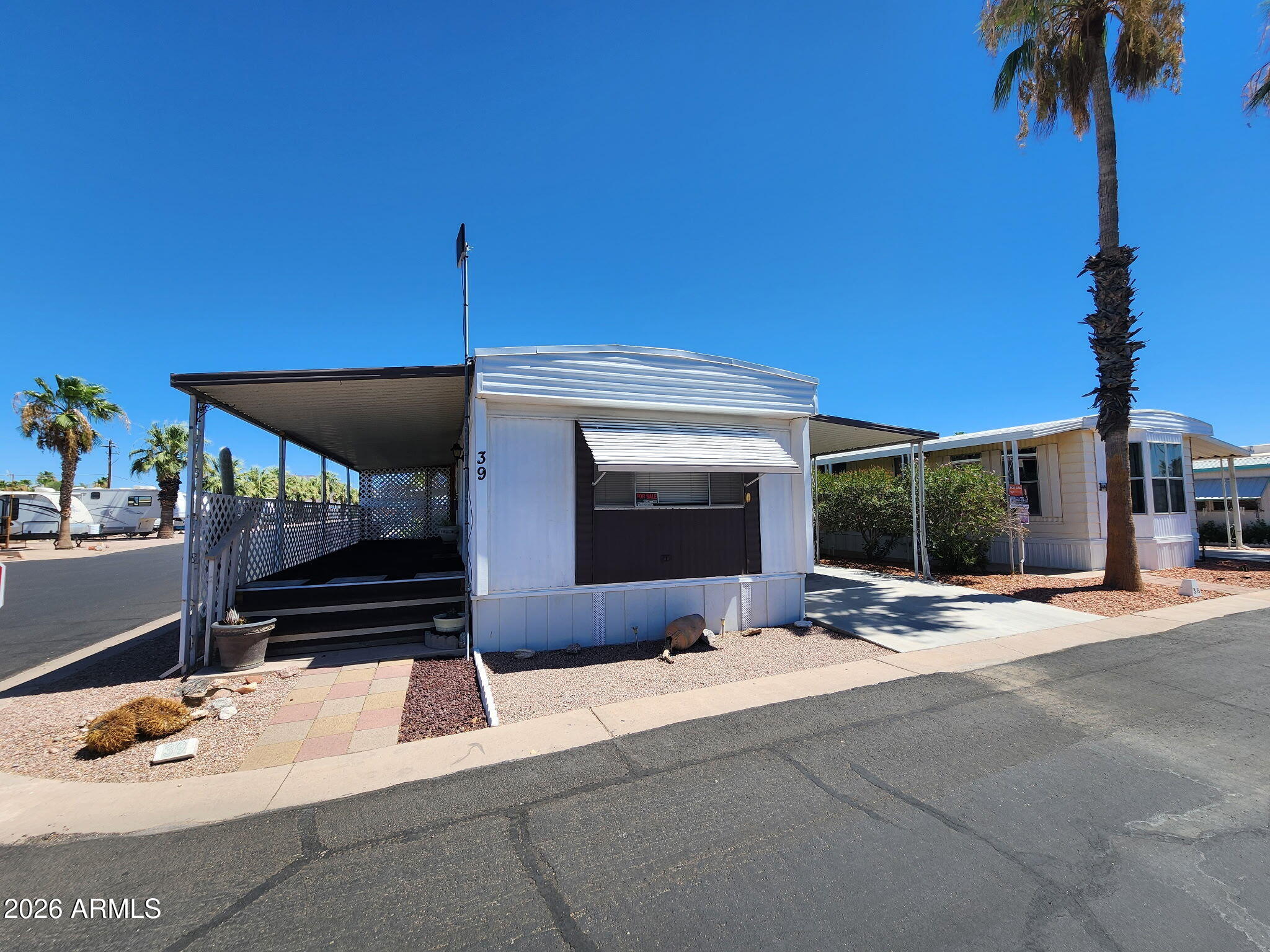Charming and well-maintained 2-bedroom, 1-bath Villager mobile home in the desirable 55+ Meridian Park community in Apache Junction! This 14x60 (840 sq ft) home features a new $10K AC unit with warranty, three ceiling fans, and layered window coverings. The updated kitchen includes a new butcher block bar, six additional cabinets, a pantry, ample storage, plus a GE stack washer/dryer and Whirlpool dishwasher. The remodeled bathroom offers added cabinetry for convenience. Enjoy a large porch with beautiful sunset views. Also includes a 2-car carport, two storage sheds and enclosed pet area with turf and direct access. Meridian Park amenities feature a year round heated pool and spa, pickleball court, dog park, fitness room, clubhouse ample social events! Conveniently located near shopping, dining, and banking, and just 25 minutes from Sky Harbor. Lot rent is $700/month and includes water, septic, and trash services.
