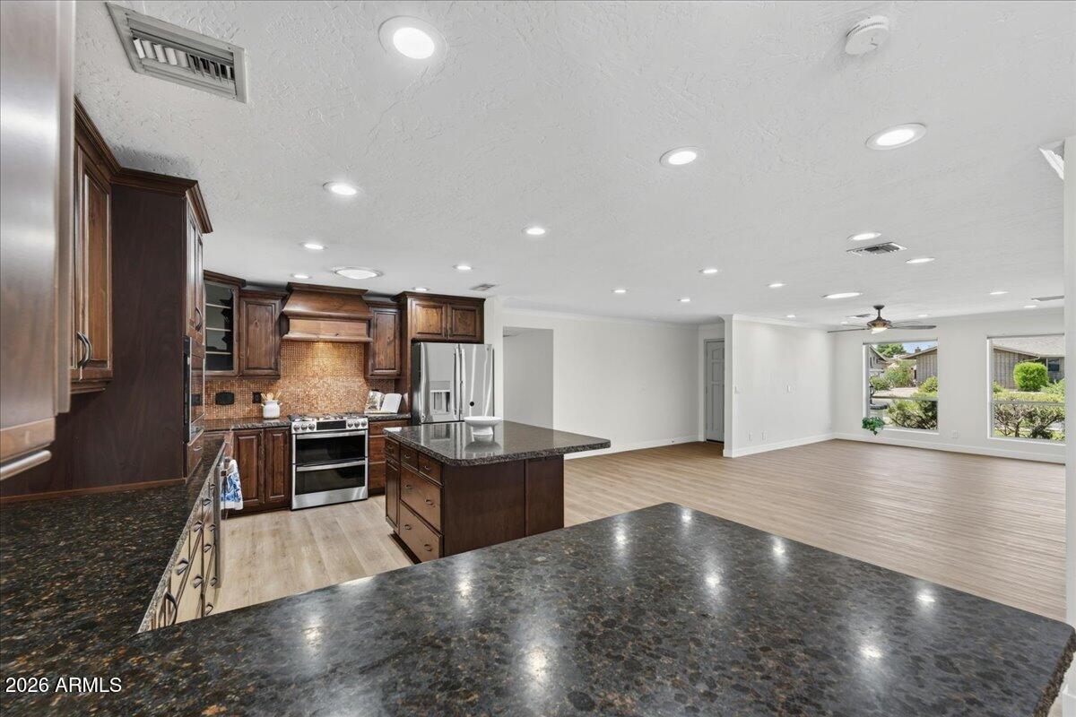 Exceptional NO HOA home in Gilburr Estates. NEW PAINT inside and out and NEW LVP flooring throughout. Nestled in the heart of Mesa, this slump block gem offers easy access to Gilbert Rd, the 60, and the 202 -- commute-friendly without sacrificing a quiet residential feel. The kitchen features rich wood cabinetry with granite counters, stainless appliances and a timeless copper farmhouse sink. A  fireplace adds warmth and style to the dining area. The primary suite includes a walk-in closet and spa-style bath, Two additional bedrooms, plus an enclosed sunroom, offer flexible space for sleeping, home office, playroom, or guest room. Out back: pavers, grass and turf, a shade sail and a built-in playground make this yard ready for everyday living. Two car garage plus 2 RV gate and street parki