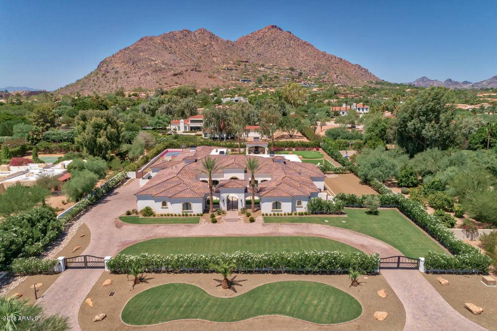 This 2017 privately gated 6 bedroom,7 bath,9,490sf Transitional 1.36 acre estate,with 2 guest suites,is located on one of the most prestigious streets in Paradise Valley.The heart of the home is an impressive dual island chef's kitchen with Wolf and Sub-Zero appliances. It flows into the family room creating 70 ft of uninterrupted open living space. The family room's full entertainment bar also services the adjoining 12 seat home theatre. Multiple motorized pocket doors open to a huge, green backyard pastureland with sport court, putting green, resort-size pool steps away from a ramada with fireplace, a BBQ area and covered entertainment patios. The home s ceilings possess beautiful attention to detail: the living room s 17 ft dark wood beamed, the dining room s coffered ceiling