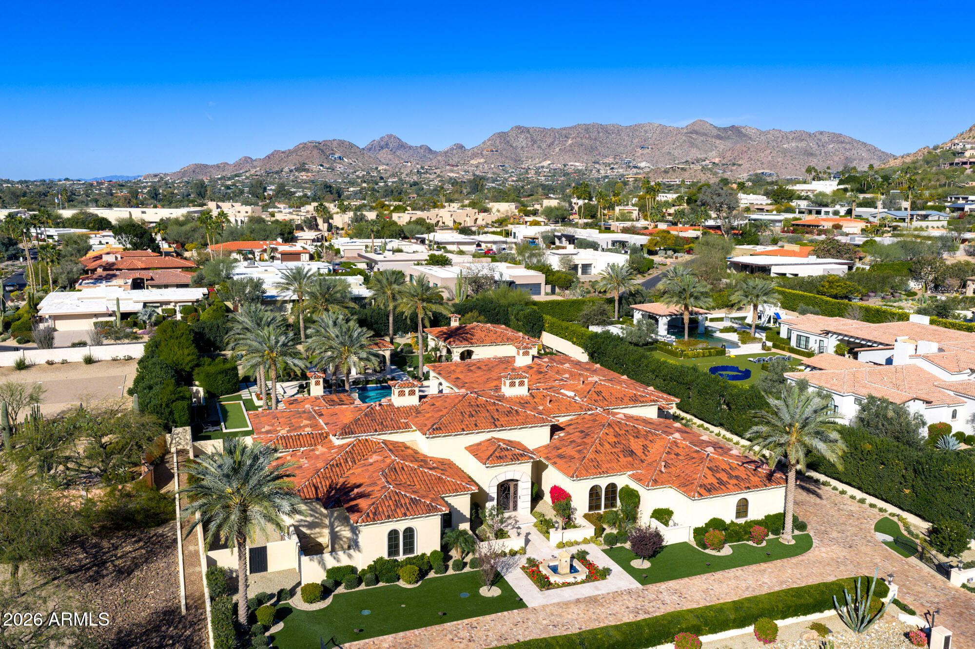 Premier 1-acre lot with breathtaking Camelback Mountain views. Experience elevated desert living in this gated Paradise Valley estate, where architectural details abound: soaring ceilings, arched entryways, multiple gas fireplaces, and stunning ceiling treatments featuring skylights, wood paneling, and exposed beams. The main residence offers an expansive open-concept layout with a grand great room, formal dining area, and a private study with custom built-ins. Entertain effortlessly with a chef's kitchen, wet bar, wine cellar, and game room, or unwind in the dedicated exercise room complete with sauna. A detached casita provides exceptional flexibility and privacy, featuring its own living room with fireplace, full kitchen, and bedroom with en-suite bath-ideal for guests or extended stay. Step outside to an extraordinary backyard retreat showcasing sweeping mountain views, tranquil fountains, and a custom pool and spa enhanced by dramatic fire and water features. Enjoy Arizona living at its finest with a ramada, covered patio, and private putting green-perfect for year-round relaxation and entertaining. Additional highlights include a 4-car garage and a premier location just minutes from world-class resorts, spas, golf, hiking, fine dining, and luxury shopping.