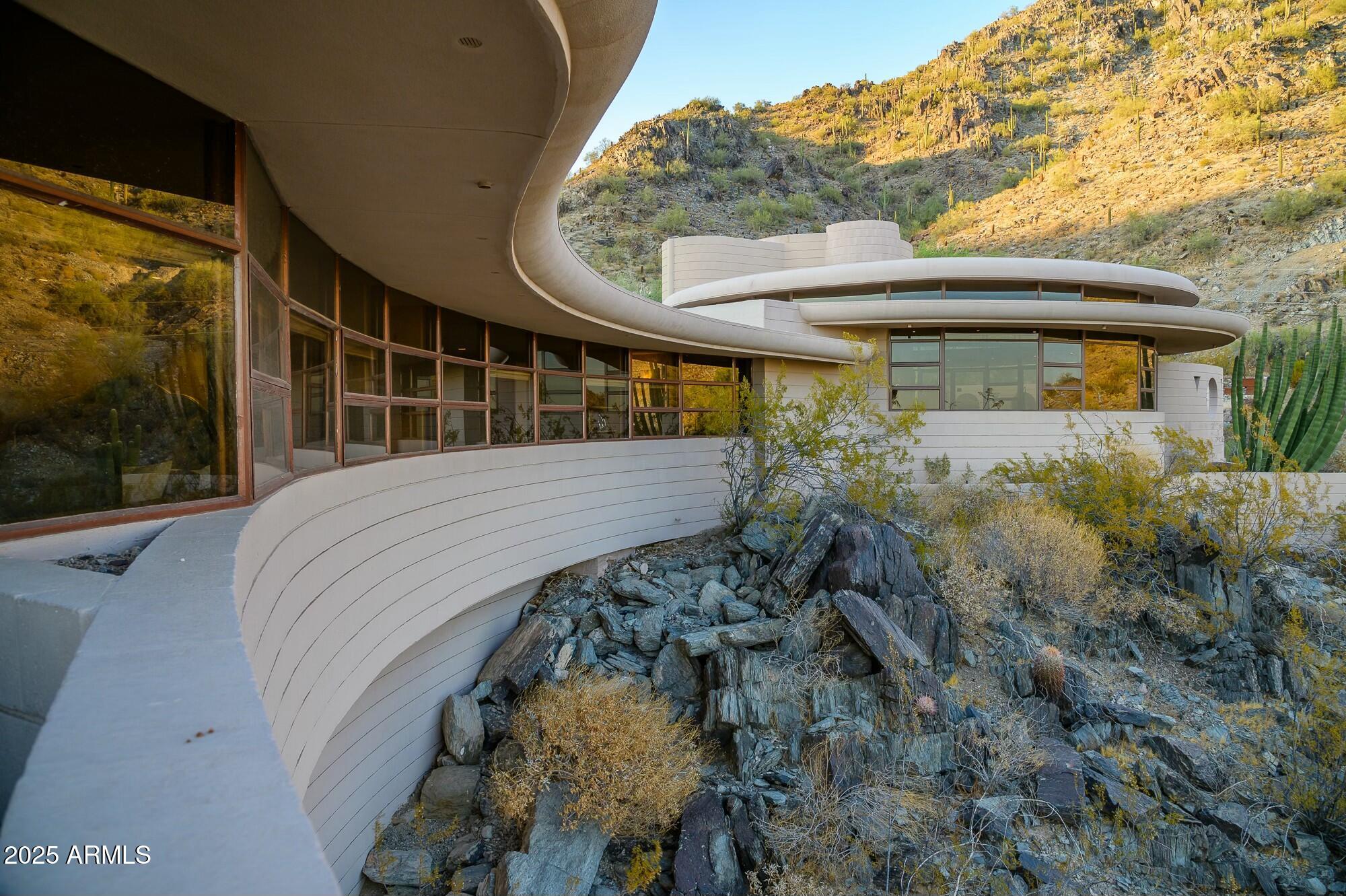 Own one of the most historic pieces of art and architecture with this famous Frank Lloyd Wright house, called The Circular Sun House / Norman Lykes. The home is  hilltop with views from every room. 3 bedrooms plus an office atop the home, a library/bar area and den with built-in entertainment cabinet could be the 4th bedroom. Designed to blend in with the curves of the surrounding desert mountain, this iconic masterpiece was the last home designed by Wright. Overlapping concentric circles create a floorplan that flows seamlessly from one room to another while every room takes in unobstructed majestic views of Palm Canyon and the city below. Curved walls, clad in golden-hued Philippine mahogany throughout cover the three bedrooms and hallway, reflecting the natural light of Palm Canyon... Sprawling entertaining spaces flow outside to ample patios and a crescent-shaped pool. See video featured in  Architectural Digest. Furniture included!
Inquire about opportunity to purchase this home with a self-directed IRA and/or fractional ownership to create an investment opportunity with this rare property.

This home was designed shortly before the completion of Frank Lloyd Wright's Guggenheim Museum in NY. Renovated in 1995. In 2019, four new Trane AC units. The kitchen is plumbed for gas (propane).  Qualified buyers only. Fractional sale once all buyers are in place.