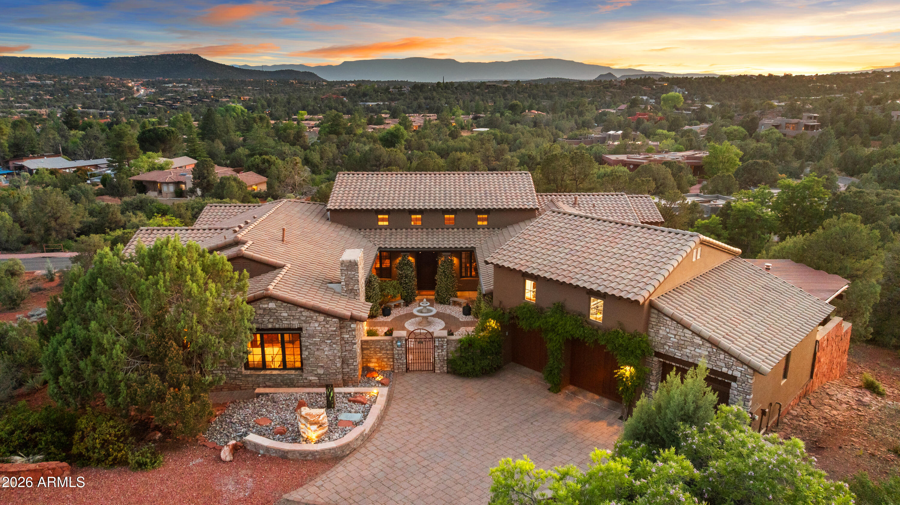 High on its own hillside in West Sedona's desirable Thunder Mountain Ranch, at the end of a private cul-de-sac, a remarkable estate awaits. An architectural gem of Italian villa-inspired living, this 5,480 sq. ft., 5-bedroom+study, 4.5-bath home delivers sweeping views, extraordinary living spaces, and the kind of outdoor entertaining areas that make every day feel like a vacation. Imagine waking to Cathedral Rock framed in your bedroom window, stepping out to a jasmine-scented courtyard where a fountain gently trickles, and ending each day watching spectacular sunsets as the sun melts behind the Mingus Mountains. Welcome to 90 Bronco Drive. Inside, the great room sets the tone - a soaring two-story stacked stone gas log fireplace anchors the great room, while generous seating and a large-screen TV, at ideal viewing height, make this a room as functional as it is beautiful. Rich wood beams flow overhead throughout the open space. Nearby, a fully appointed bar offers excellent seating for entertaining, abundant bottle storage, and a beverage cooler. French doors open out to an elevated balcony with long-range views to Cockscomb and the Mingus Mountains.
The gourmet kitchen is equally impressive: Viking 6-burner cooktop, Wolf double ovens, SubZero refrigeration, and a wall of windows above that pulls in dramatic views of Little Sugarloaf, Chimney Rock, and epic sunsets. Chefs will also appreciate the dedicated butcher block counter, the spacious walk-in pantry, and the butler's pantry. The dining room strikes the perfect balance between grand and intimate, with two sets of French doors that open to both the west terrace and the loggia courtyard. The west terrace, modeled after a true Italian villa, features an authentic wood-burning pizza oven, covered seating, open-air flagstone entertaining space, and the most spectacular Sedona sunsets imaginable.
The main-level primary suite offers some of the most exclusive and private views in all of West Sedona. Perched on the southwest corner of the property, it overlooks the community's abundant open space and has long-range views to the iconic Cathedral Rock and the entire Mingus Mountain range. Enjoy the warmth of the gas log fireplace, the cozy fireside seating, and the private balcony where you can breathe it all in from your own corner of the world. The primary bath offers a generously appointed double vanity with abundant storage, a spacious walk-in shower, and a jetted tub framed by a large picture window. A dual-winged closet with direct laundry room access completes the suite.
The main level also features an additional en suite guest bedroom, complete with its own access to the courtyard, a gas log fireplace, and kitchenette. The partner's study is also located off this wing of the home, opening across the hall through French doors to the courtyard. These functional spaces round out the home's 3,578 sq. ft. single-level, stair-free main level.
The lower level adds 1,902 sq. ft. of additional living space. Here you'll find a generous living area, a spacious second primary suite with walk-in closet and private bath, and two additional bedrooms that share a bath. This level opens onto a long, covered patio overlooking acres of green space and the Mingus Mountains beyond.
This exceptionally designed estate features more than 1,700 sq. ft. of covered and open balconies, patios, exterior walkways, loggias, and open terraces - providing shade, entertaining, and functional living space. An oversized 891 sq. ft. three-car garage with full built-in workbench and abundant storage cabinets rounds out this exceptional property. 90 Bronco Drive is where La Dolce Vita meets the the iconic red rocks of Sedona - a retreat, a lifestyle, and a rare opportunity to live at the top of one of West Sedona's most coveted addresses.

Note: All furniture and artwork can be conveyed with an appropriate offer, excluding the linens in the primary bedroom.

See MLS "Docs" tab for features to note/upgrades.